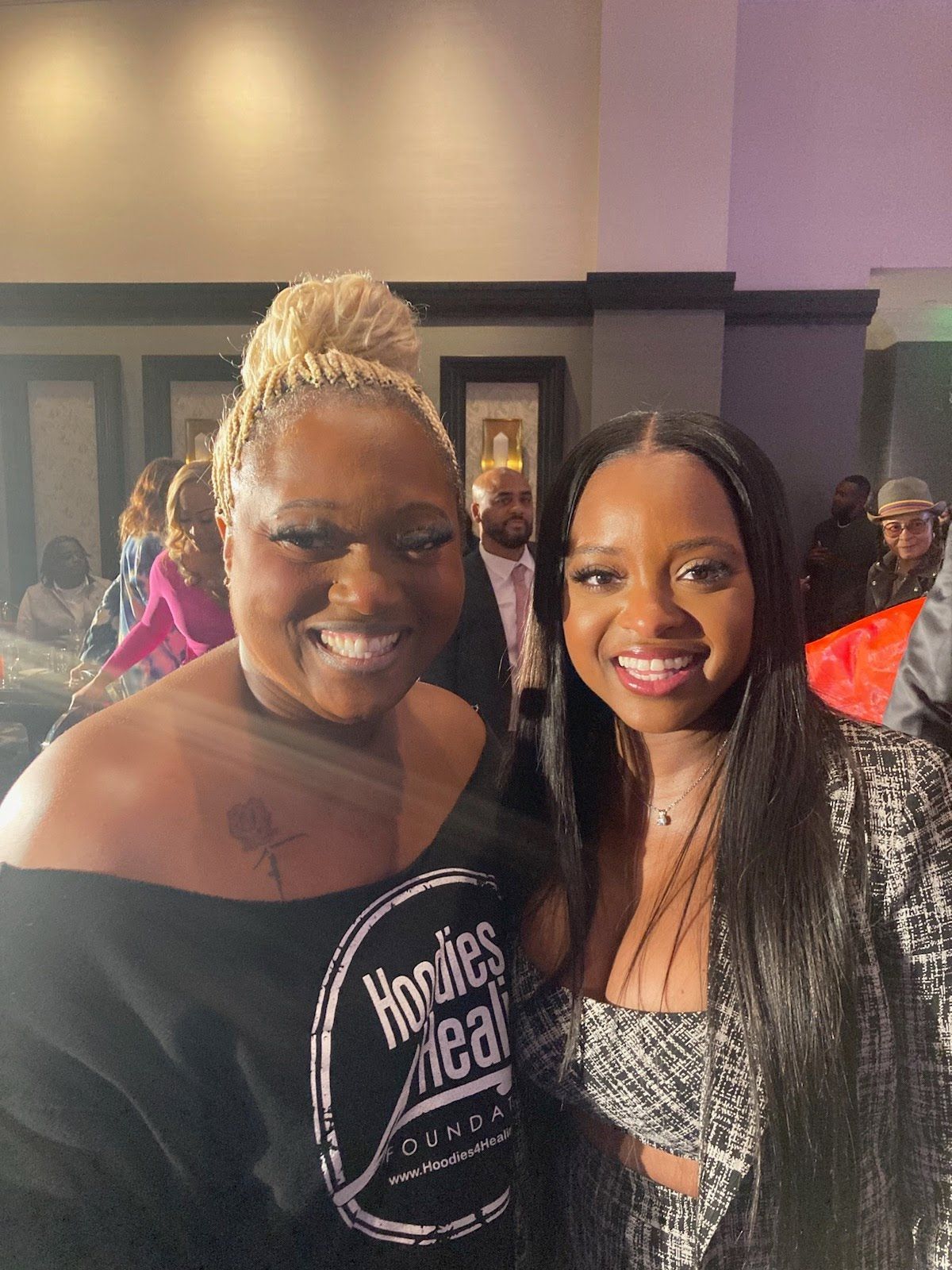 Two women are posing for a picture and one is wearing a shirt that says hobbies are real