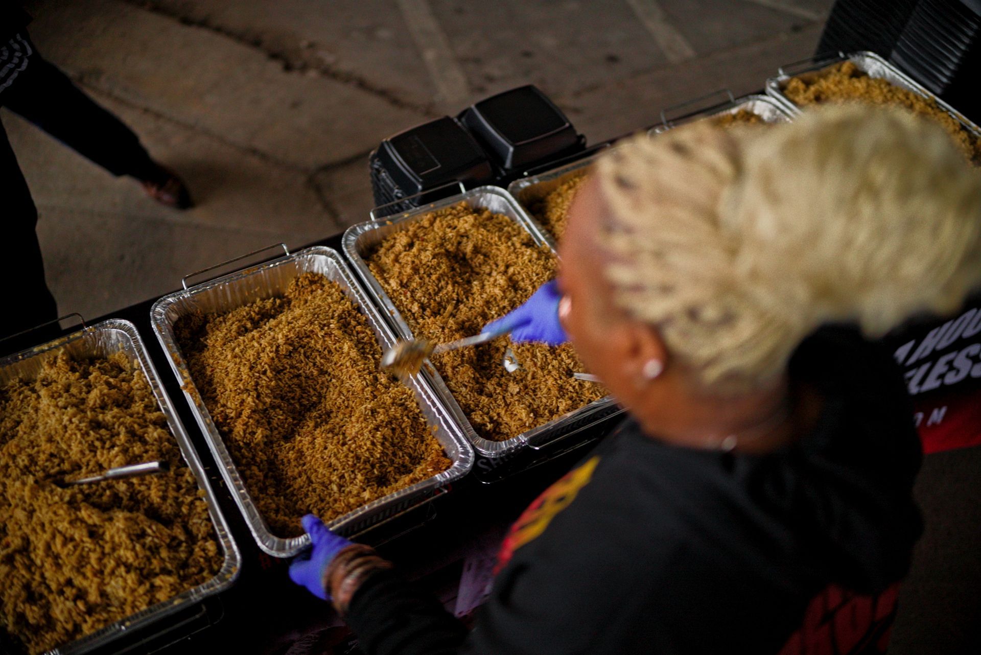 A woman is eating food from a tray while wearing blue gloves.