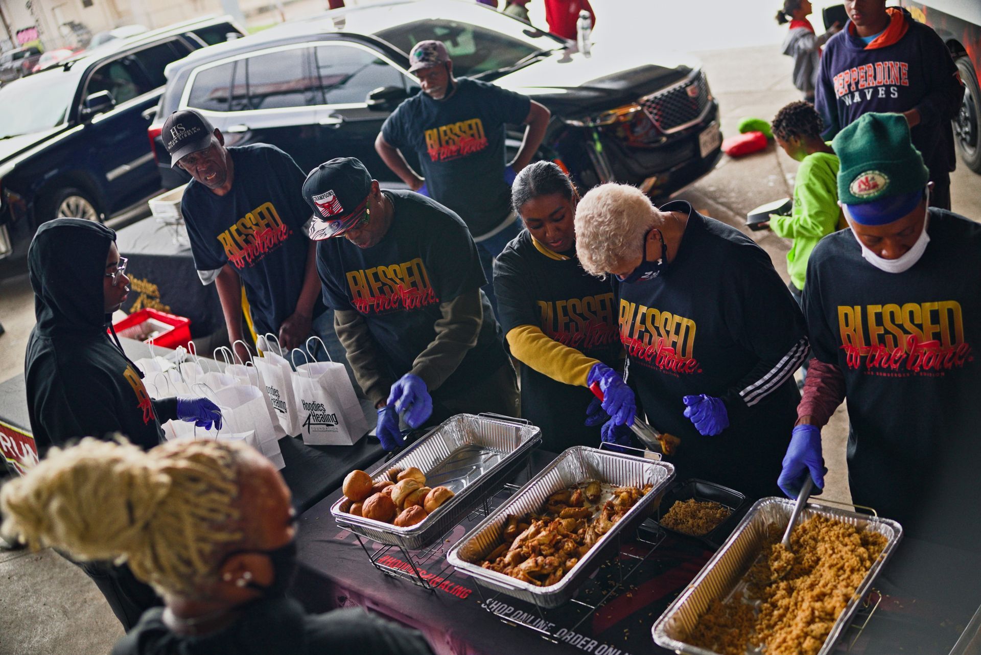 A group of people are standing around a table with trays of food.