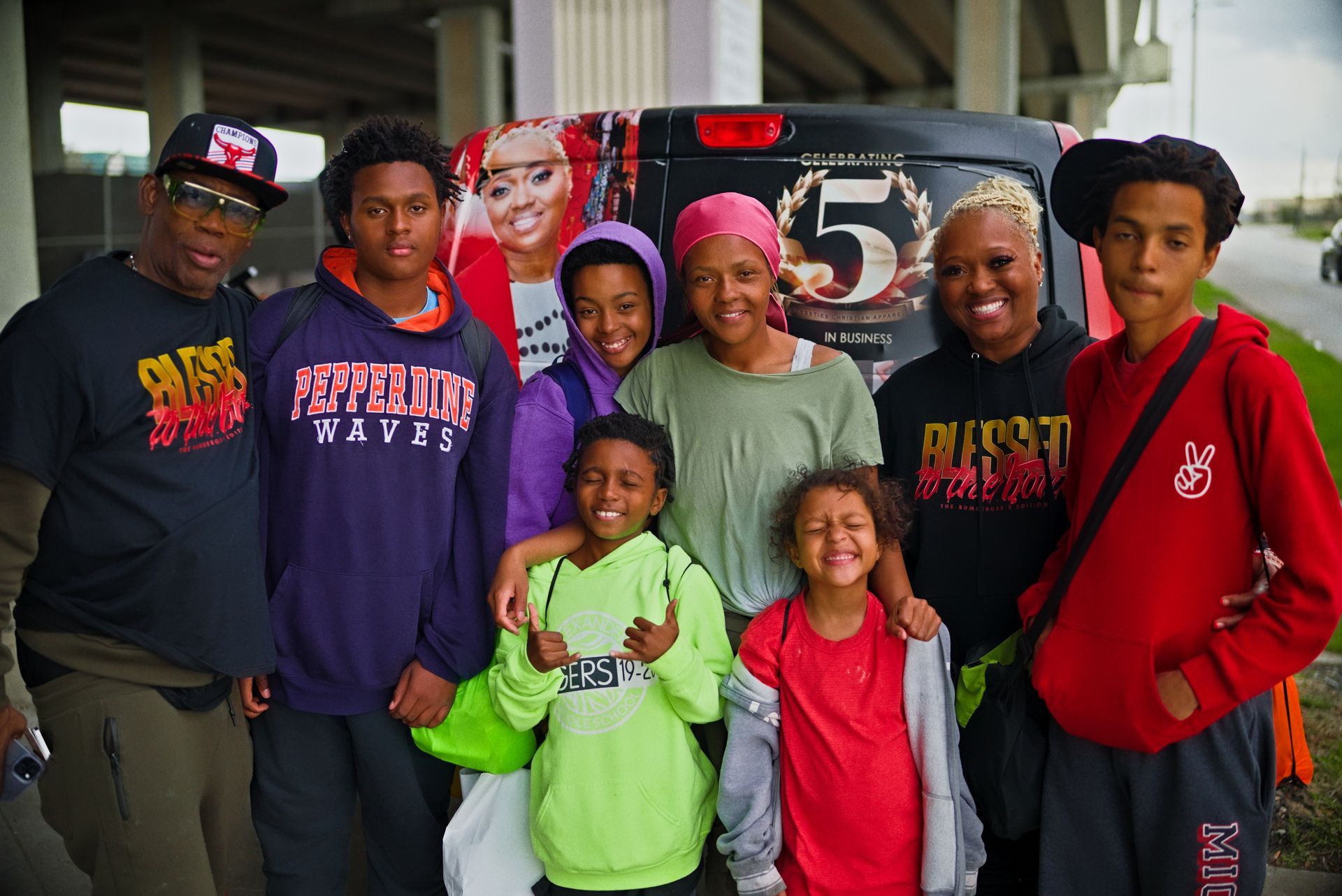 A group of people posing for a picture in front of a van with the number 5 on it