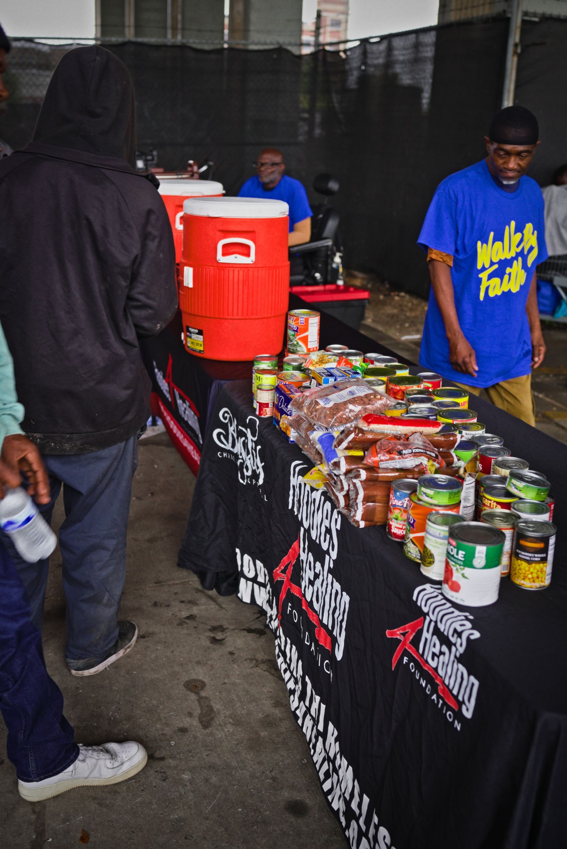 A man in a blue shirt stands in front of a table full of food
