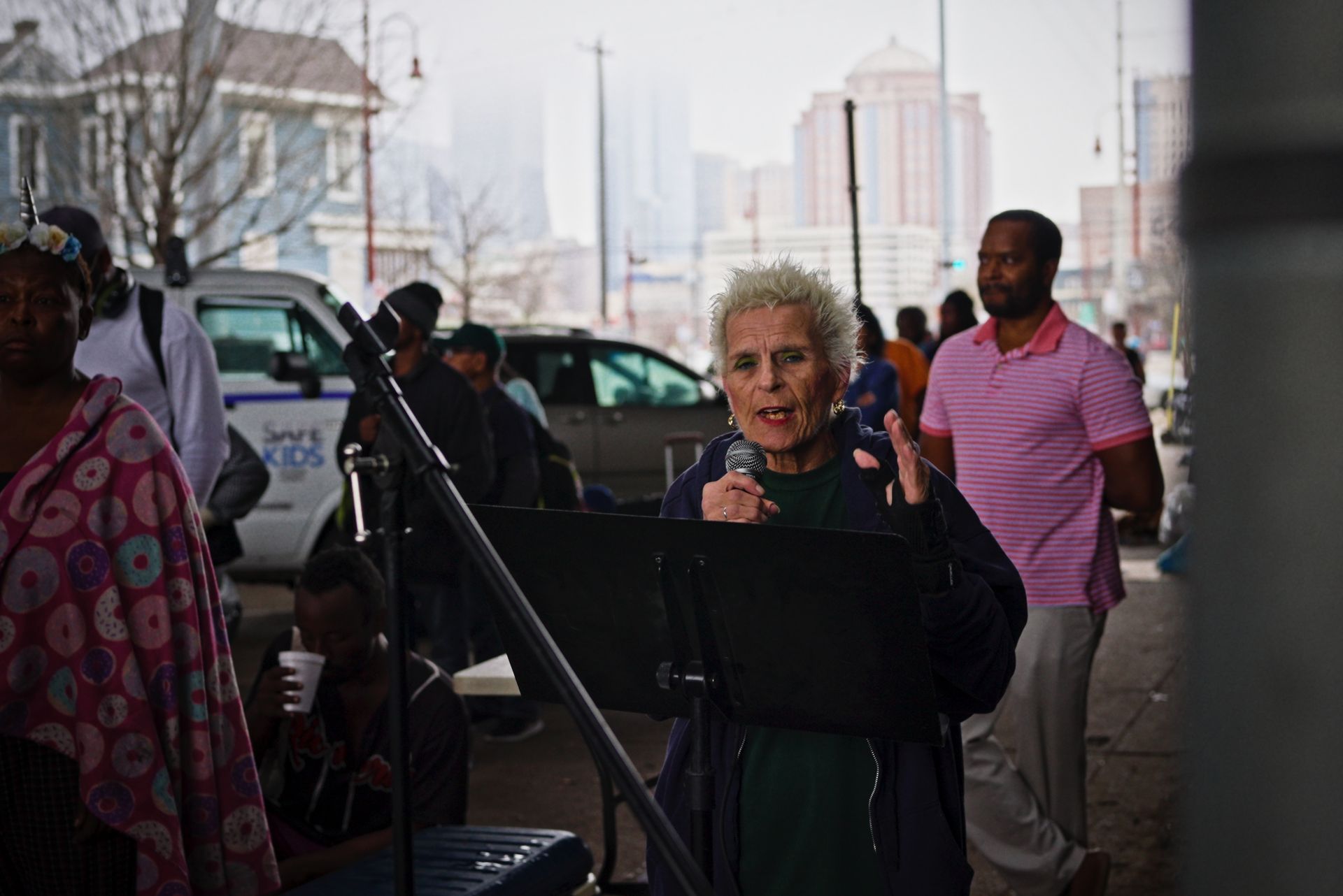 A woman is standing in front of a microphone in a crowd of people.