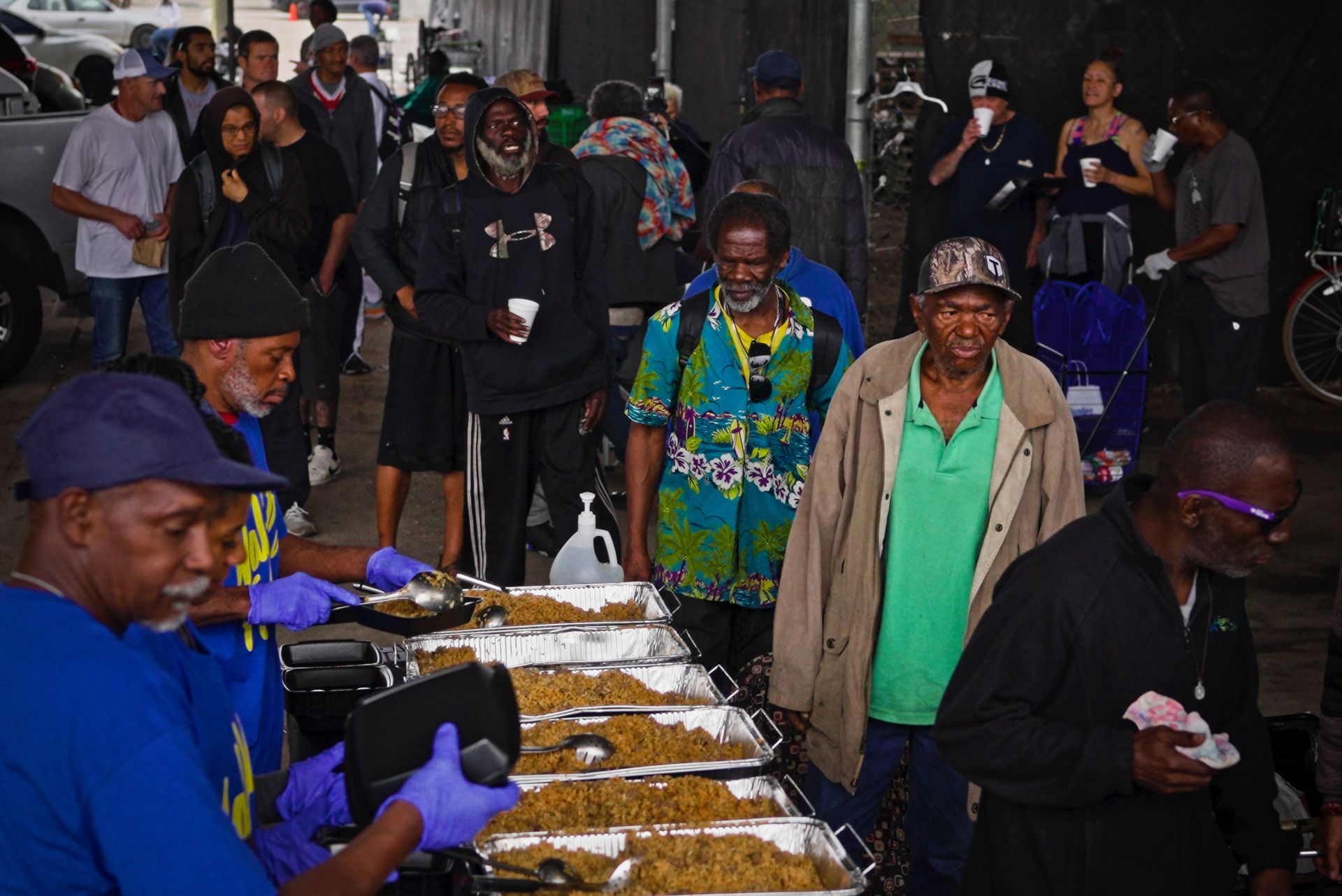 A group of people are standing around trays of food.