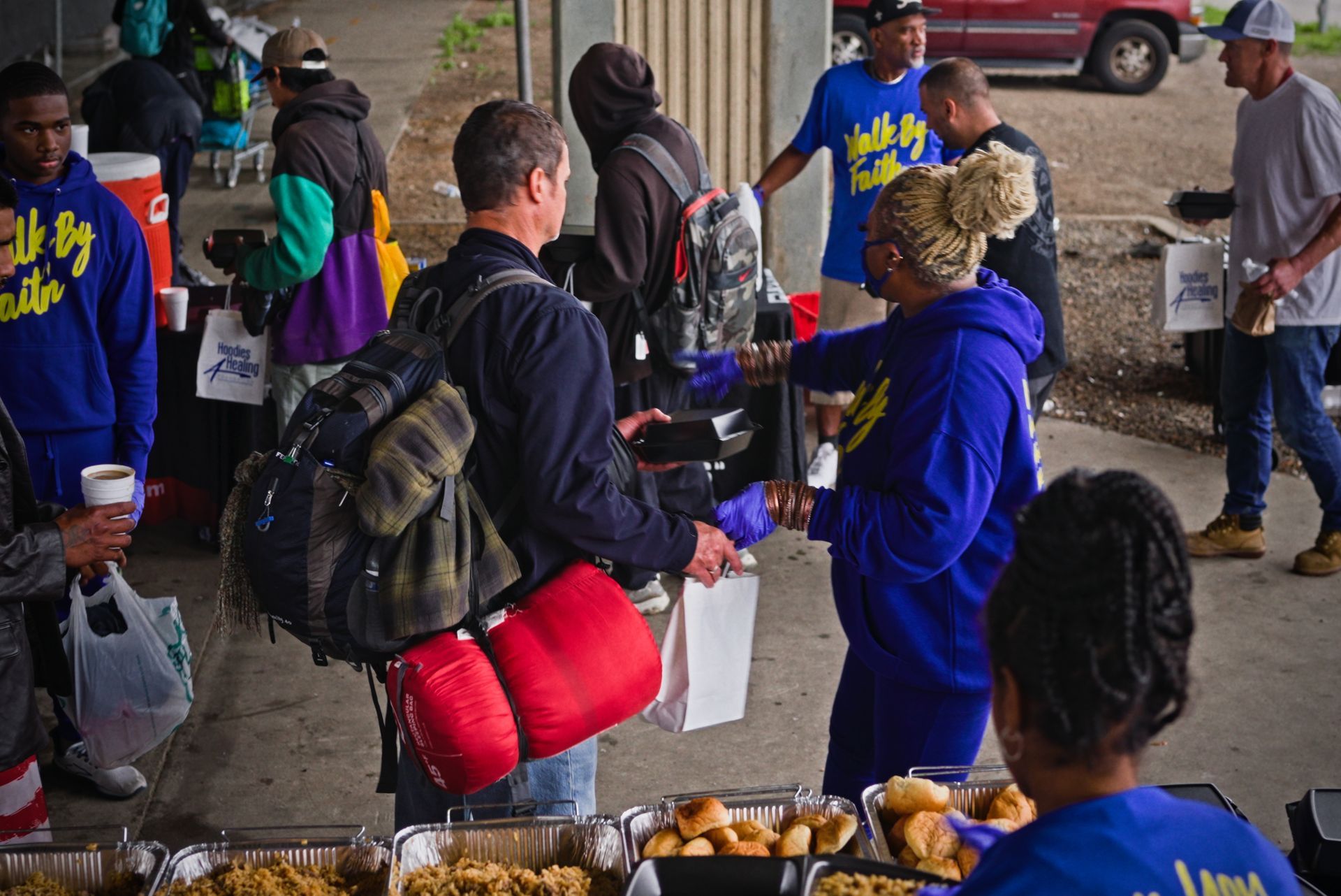 A group of people are standing around a table eating food.
