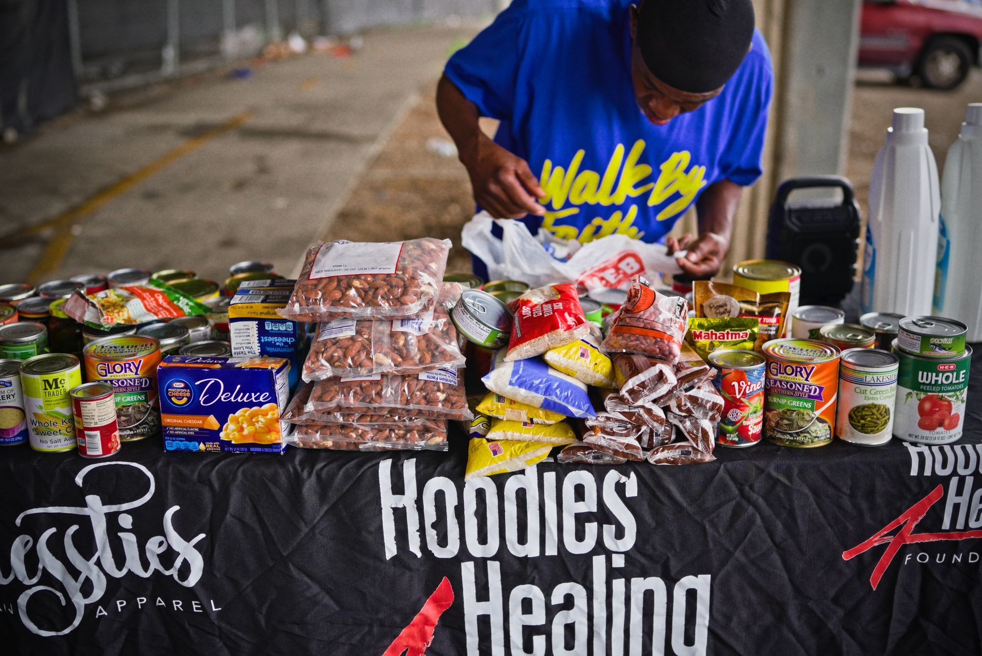 A man standing behind a table that says hoodies healing