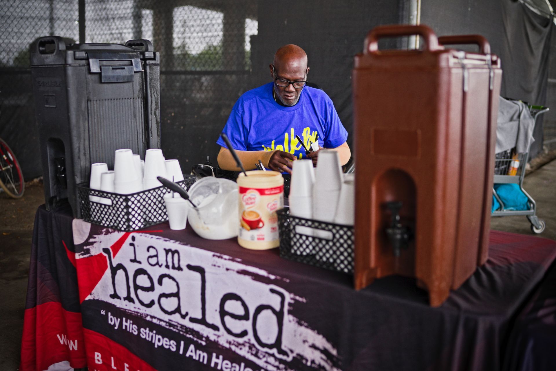 A man is sitting at a table with a sign that says i am healed