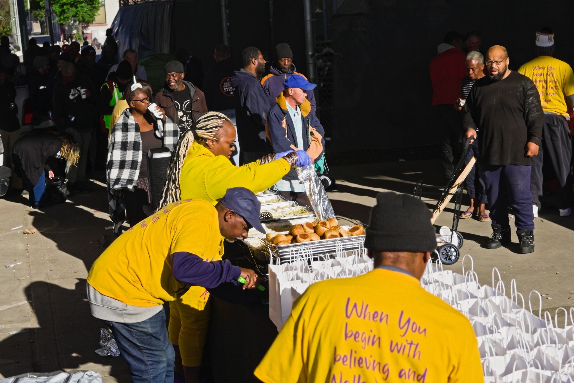 A man wearing a yellow shirt that says when you begin with believing