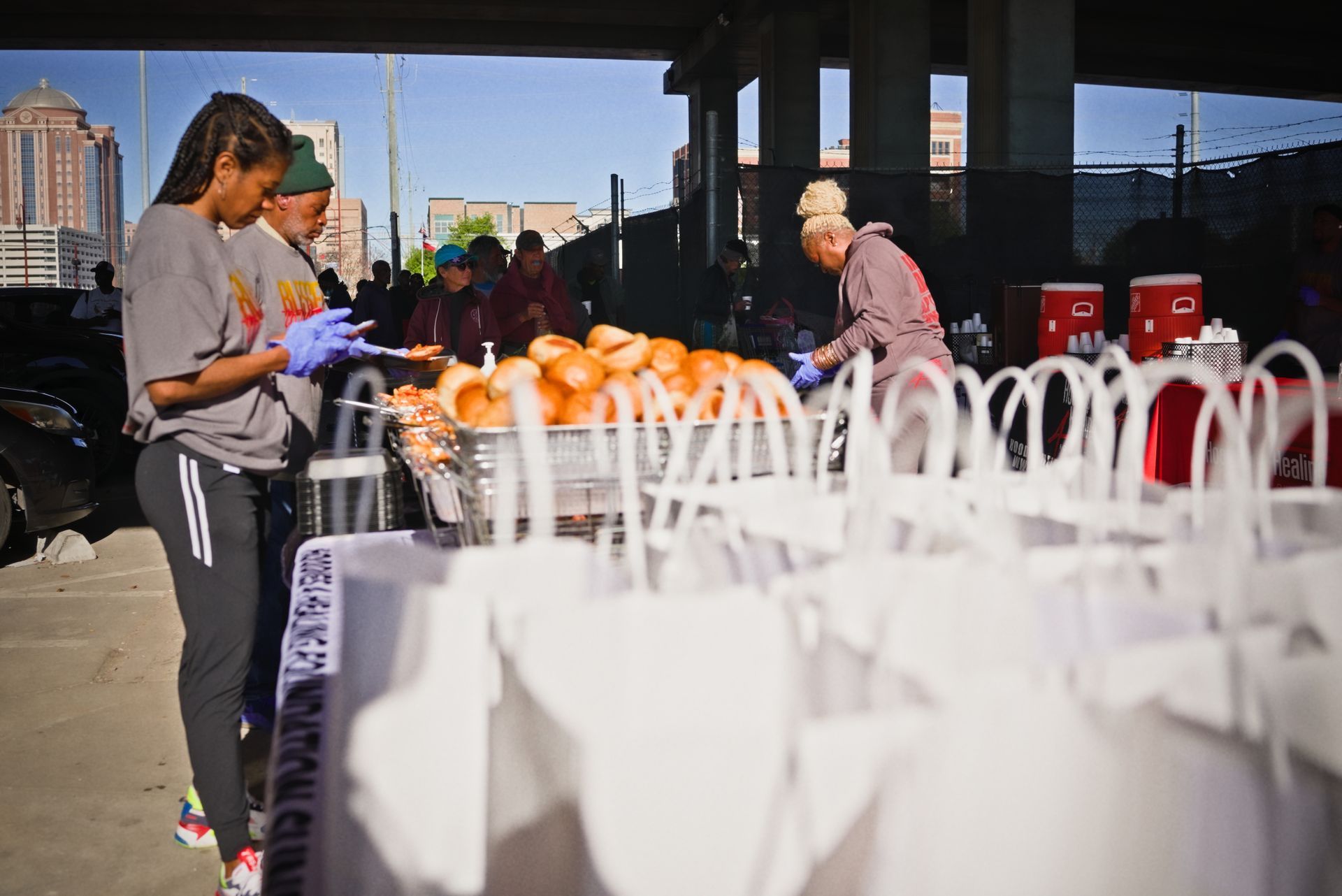 A group of people are standing around a table filled with white bags.