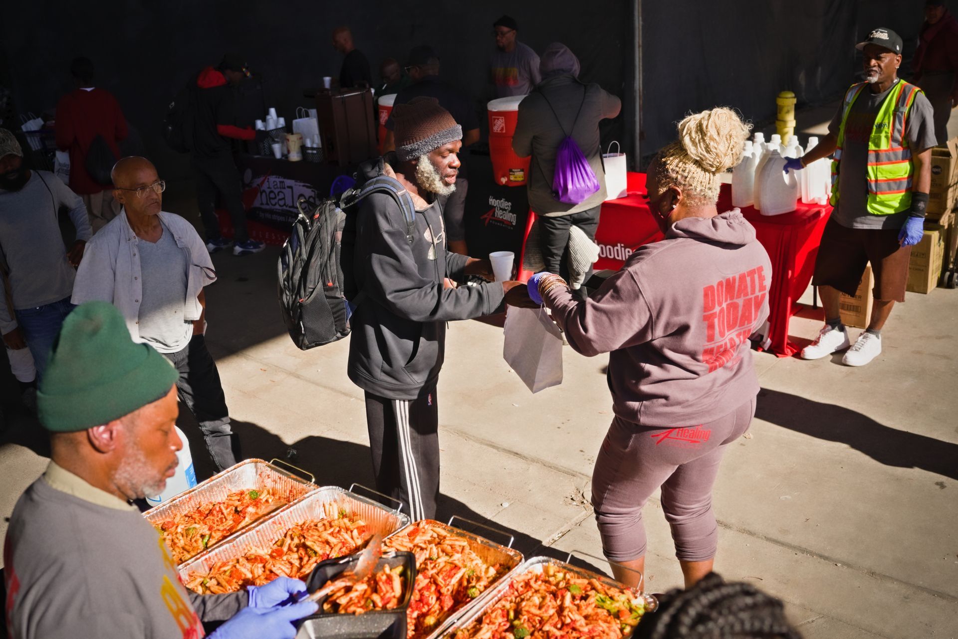 A group of people are standing around a table with food.