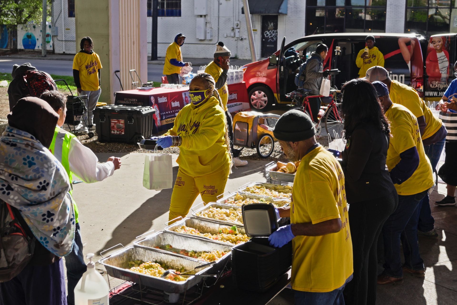 A group of people are standing around a table filled with food.