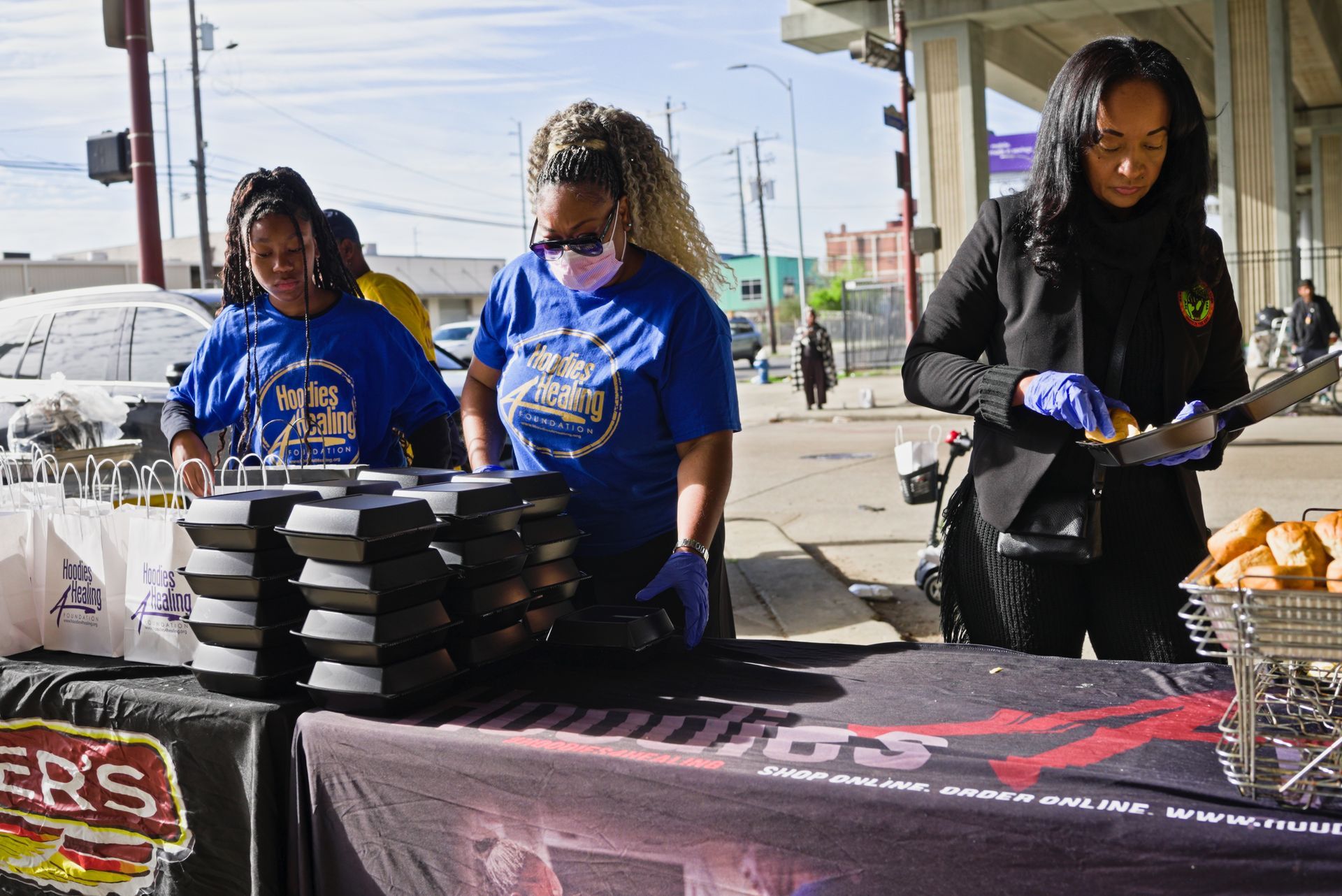 A group of women are standing around a table preparing food.
