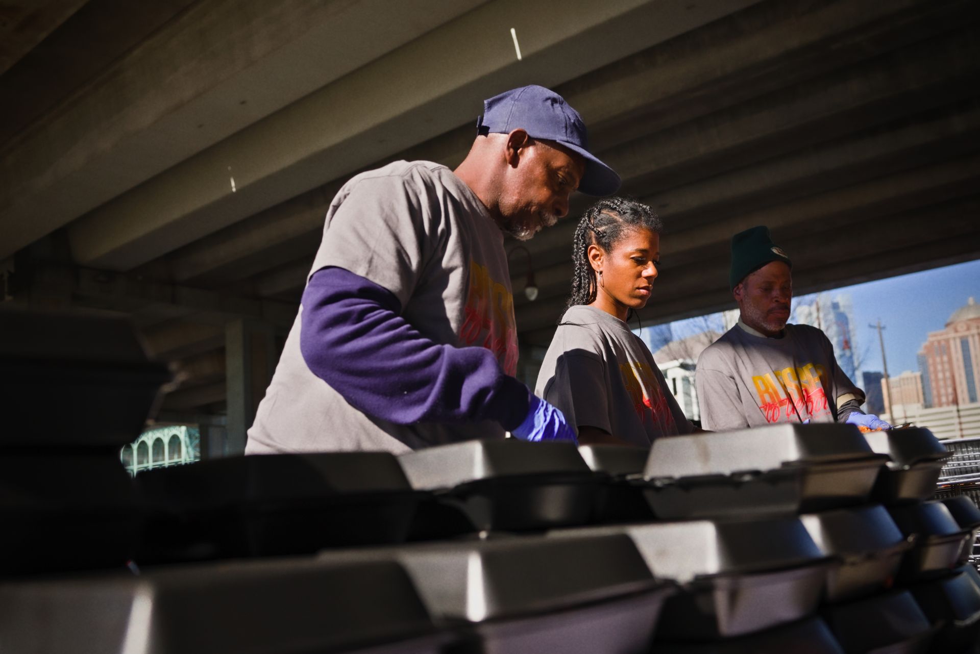 A man and a woman are working on a pile of boxes under a bridge.