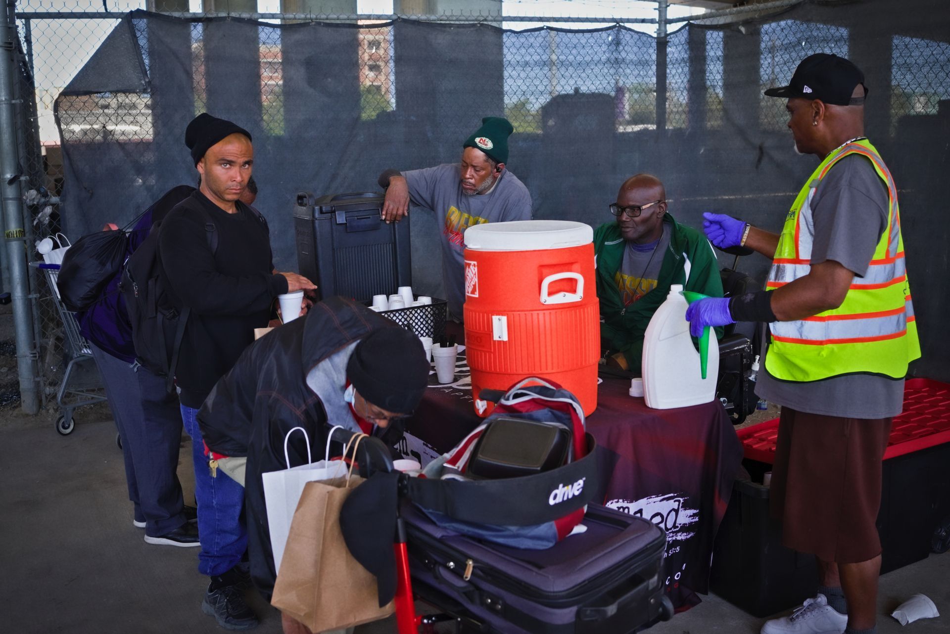 A group of people are standing around a table with luggage and a water cooler.