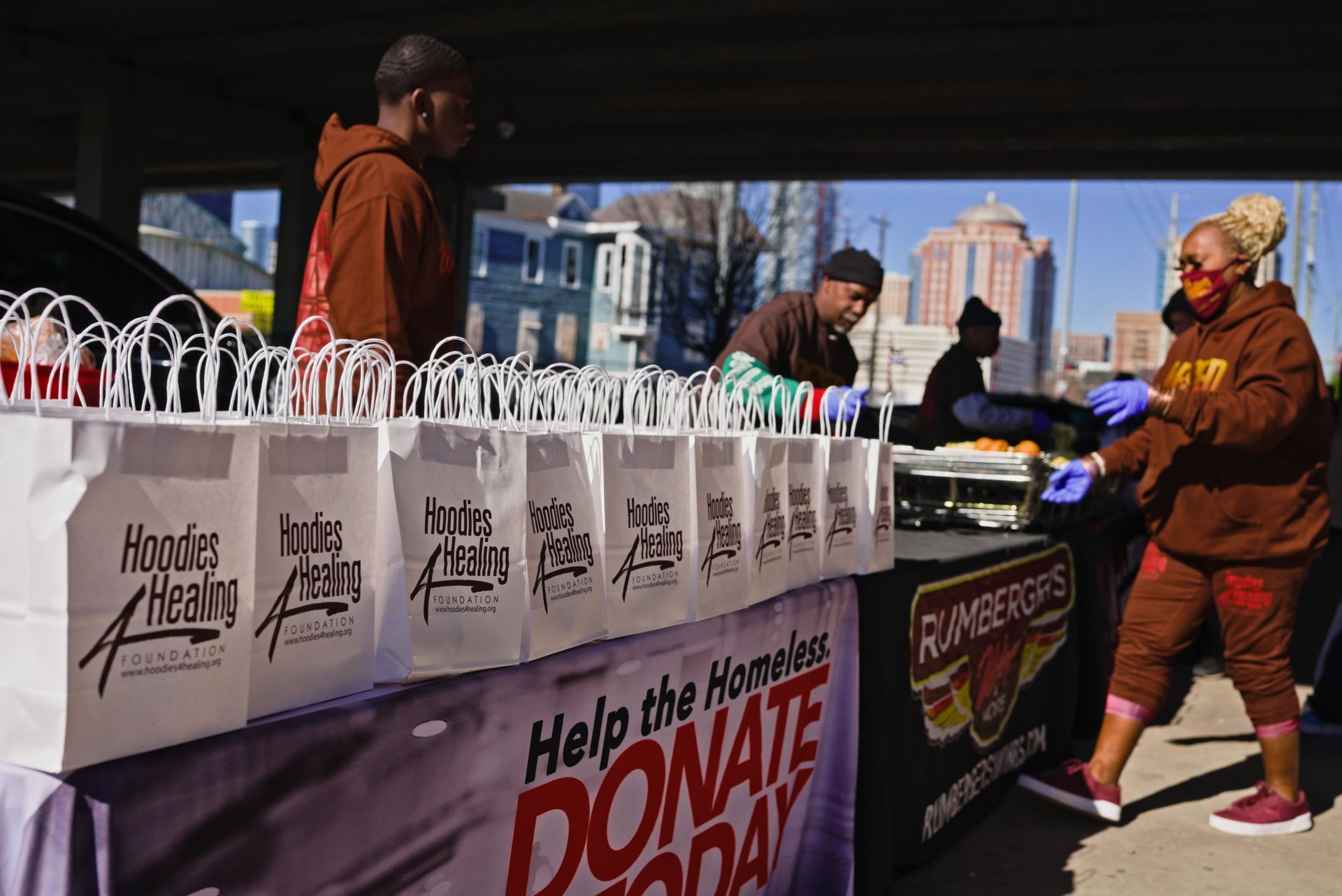 A group of people are standing around a table with bags on it.