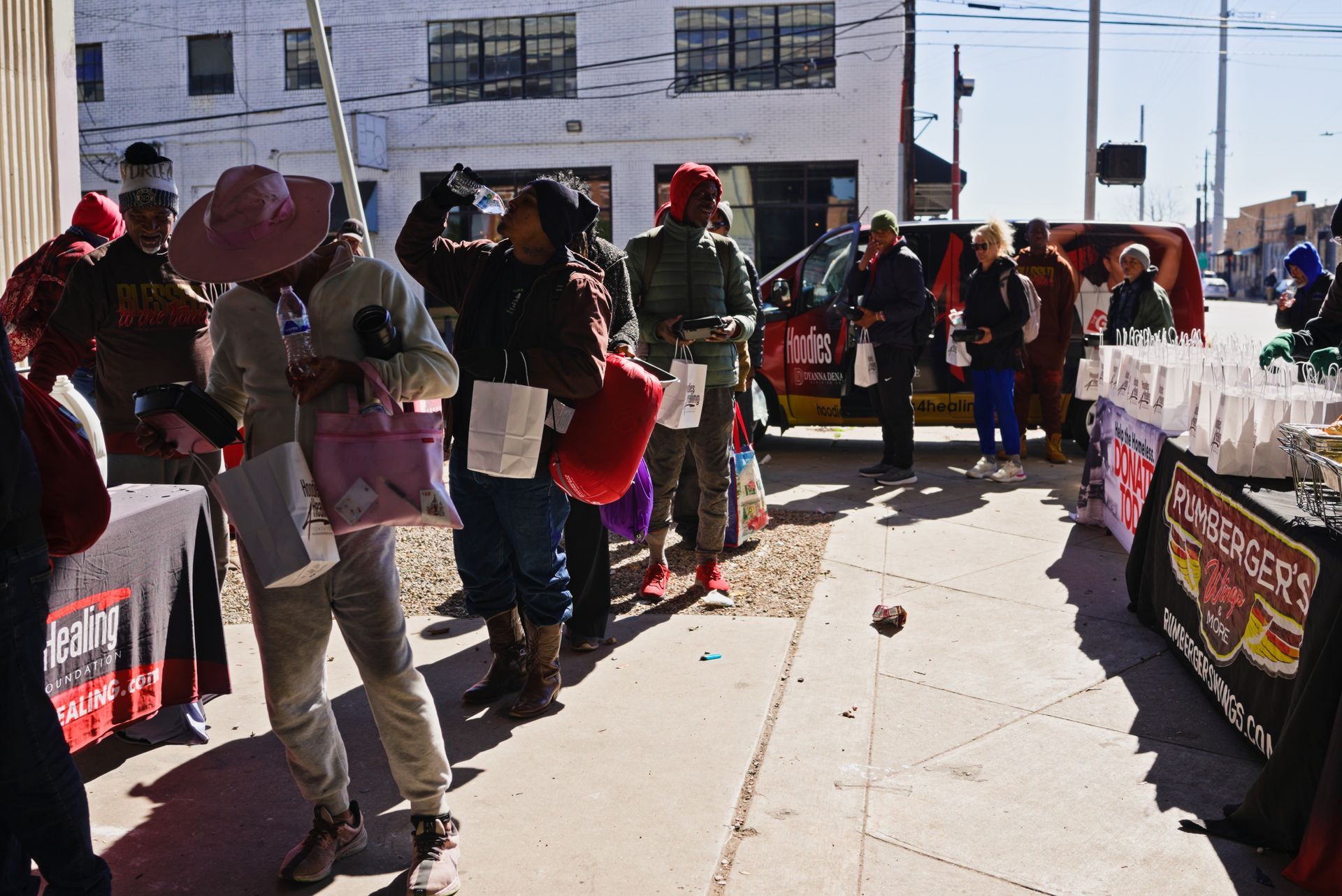A group of people are standing on a sidewalk in front of a store.