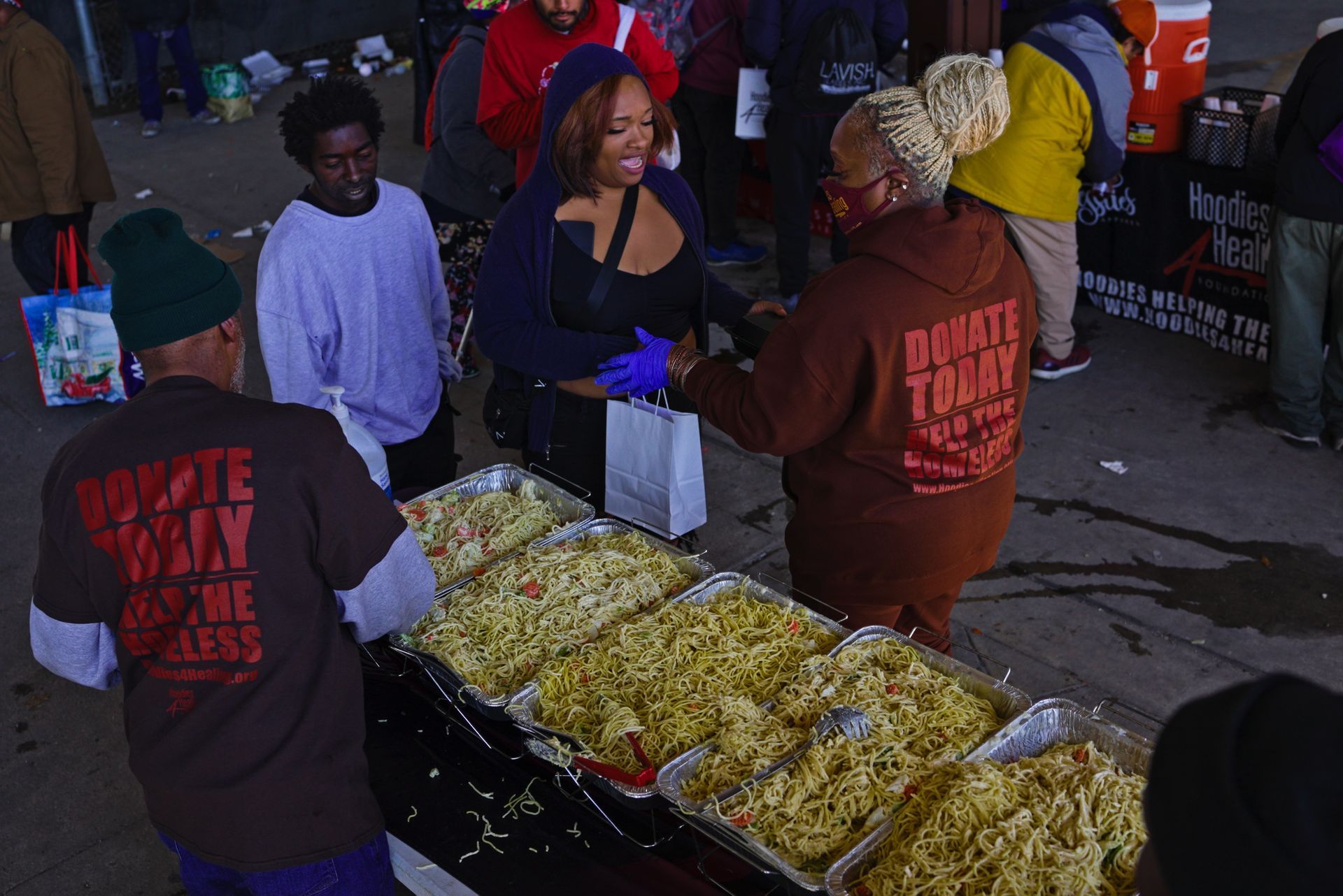 A group of people are standing around a table filled with food.