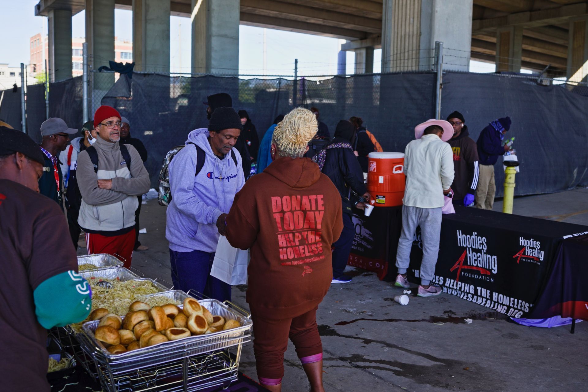 A group of people are gathered around a table with a woman wearing a hoodie that says bake it tart