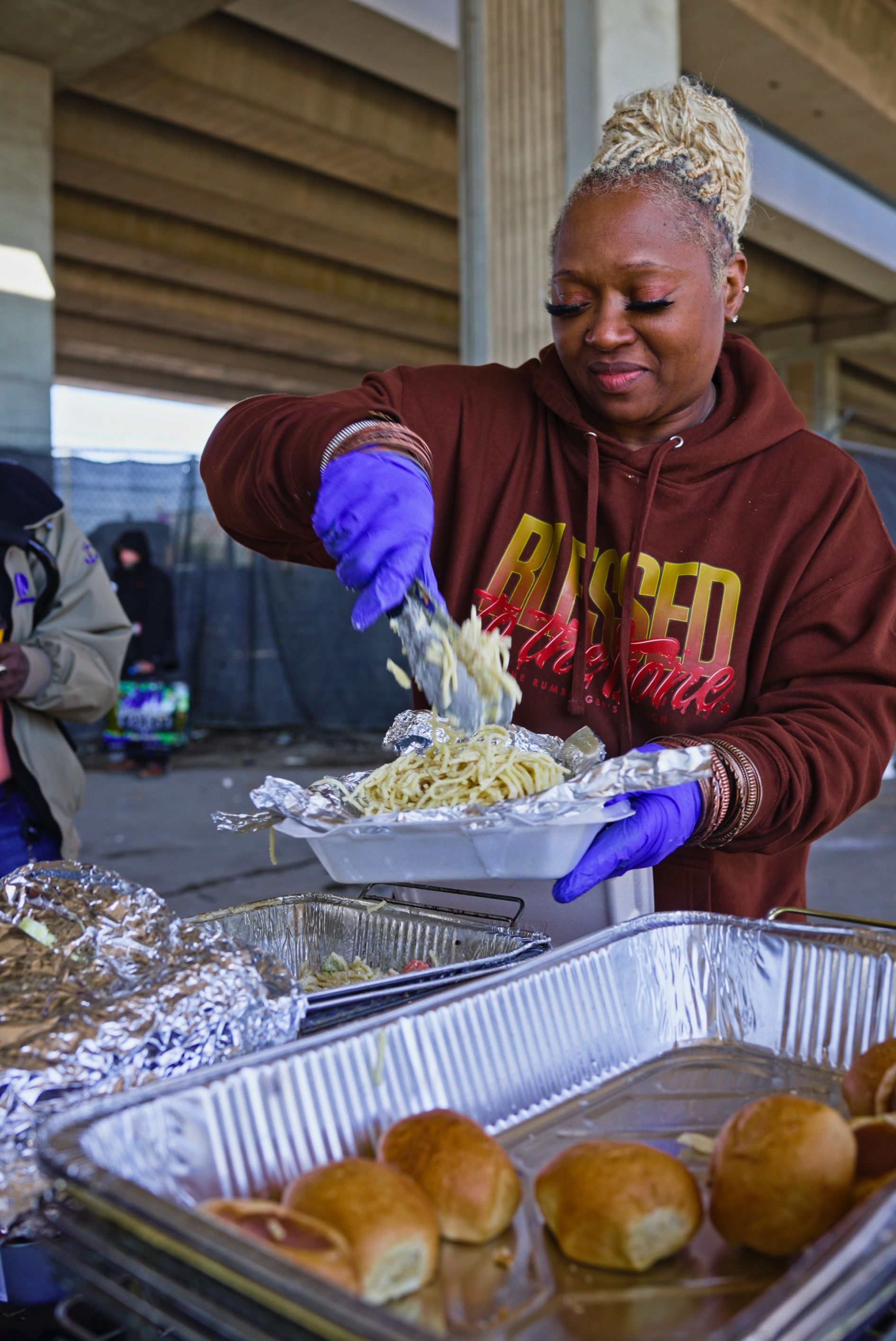 A woman in purple gloves is serving food to a group of people.