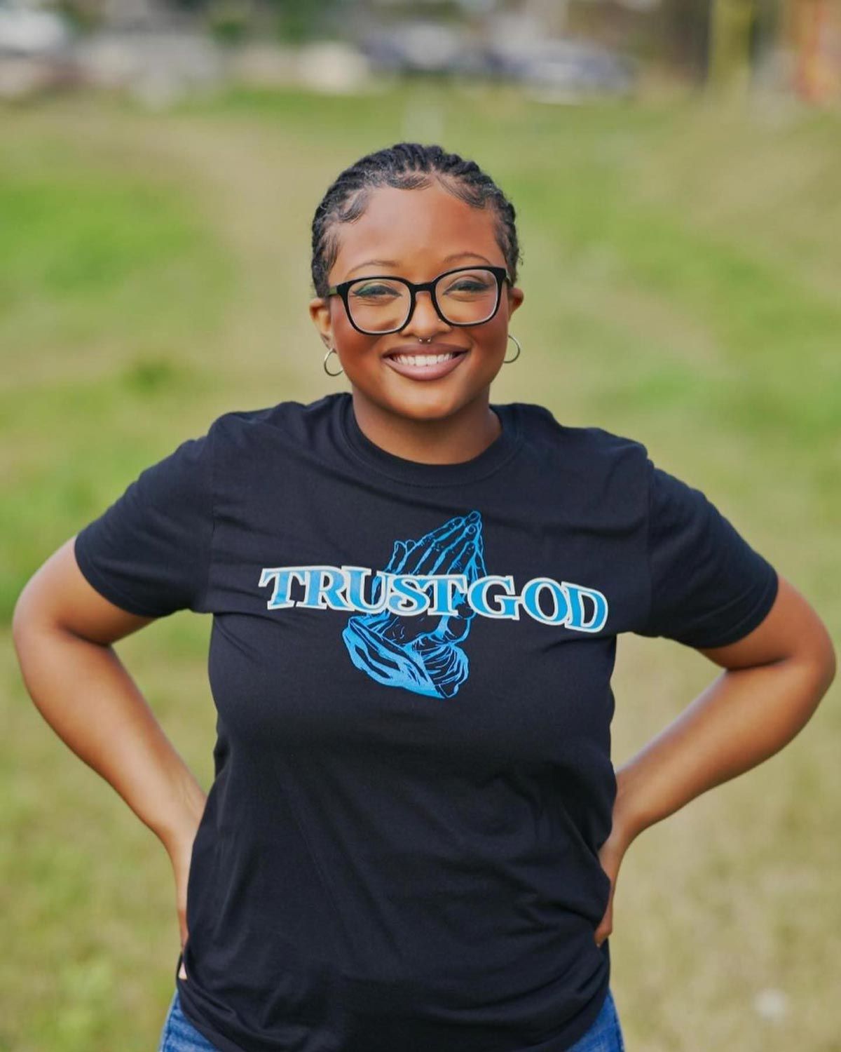 A woman wearing a black t-shirt that says trust god