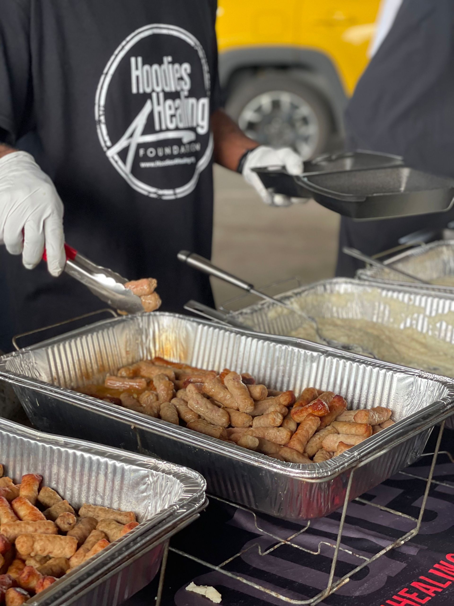 A person wearing a shirt that says hoodies heating is serving food