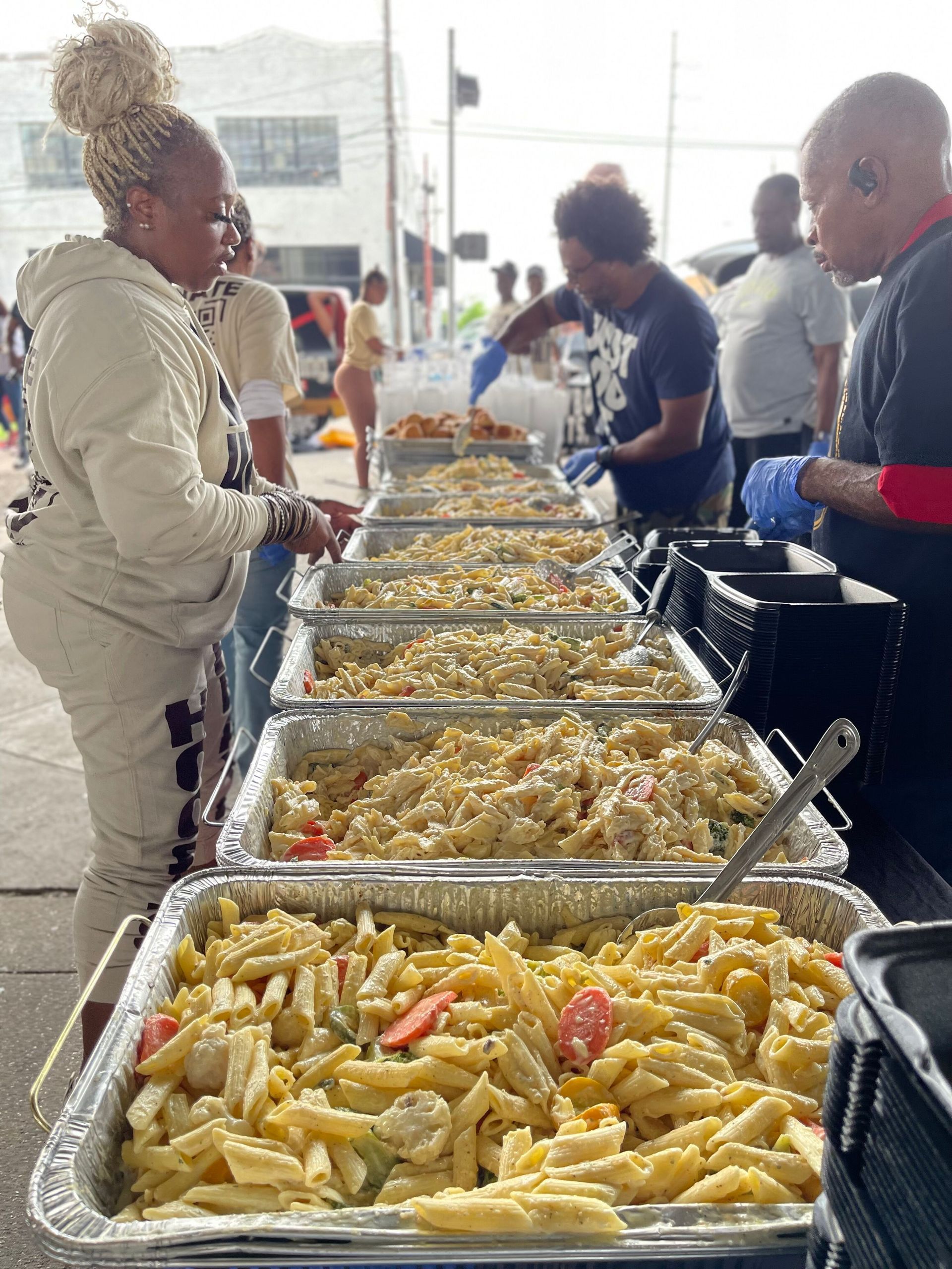 A woman is standing in front of a long table filled with trays of food.