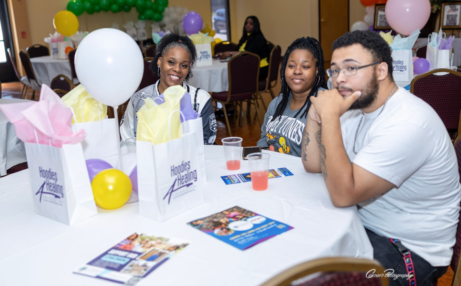 A group of people are sitting at a table with balloons.