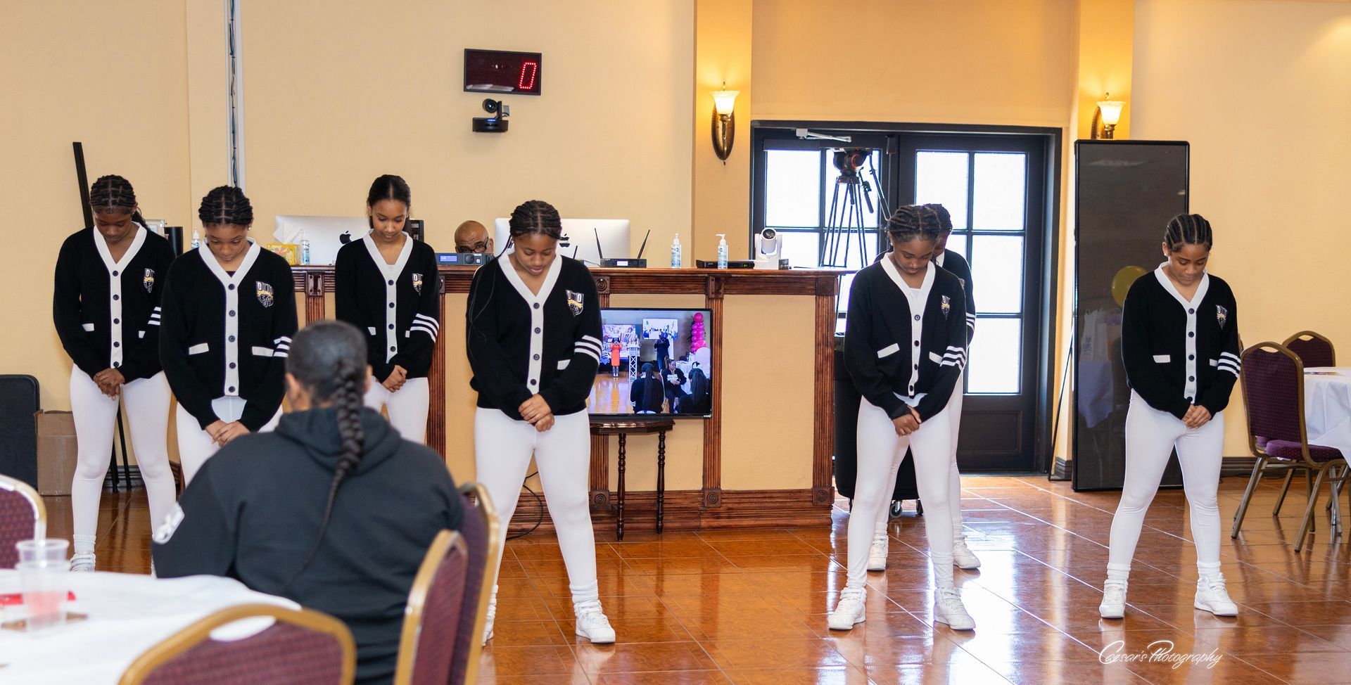 A group of young girls are dancing in a room while a woman watches.