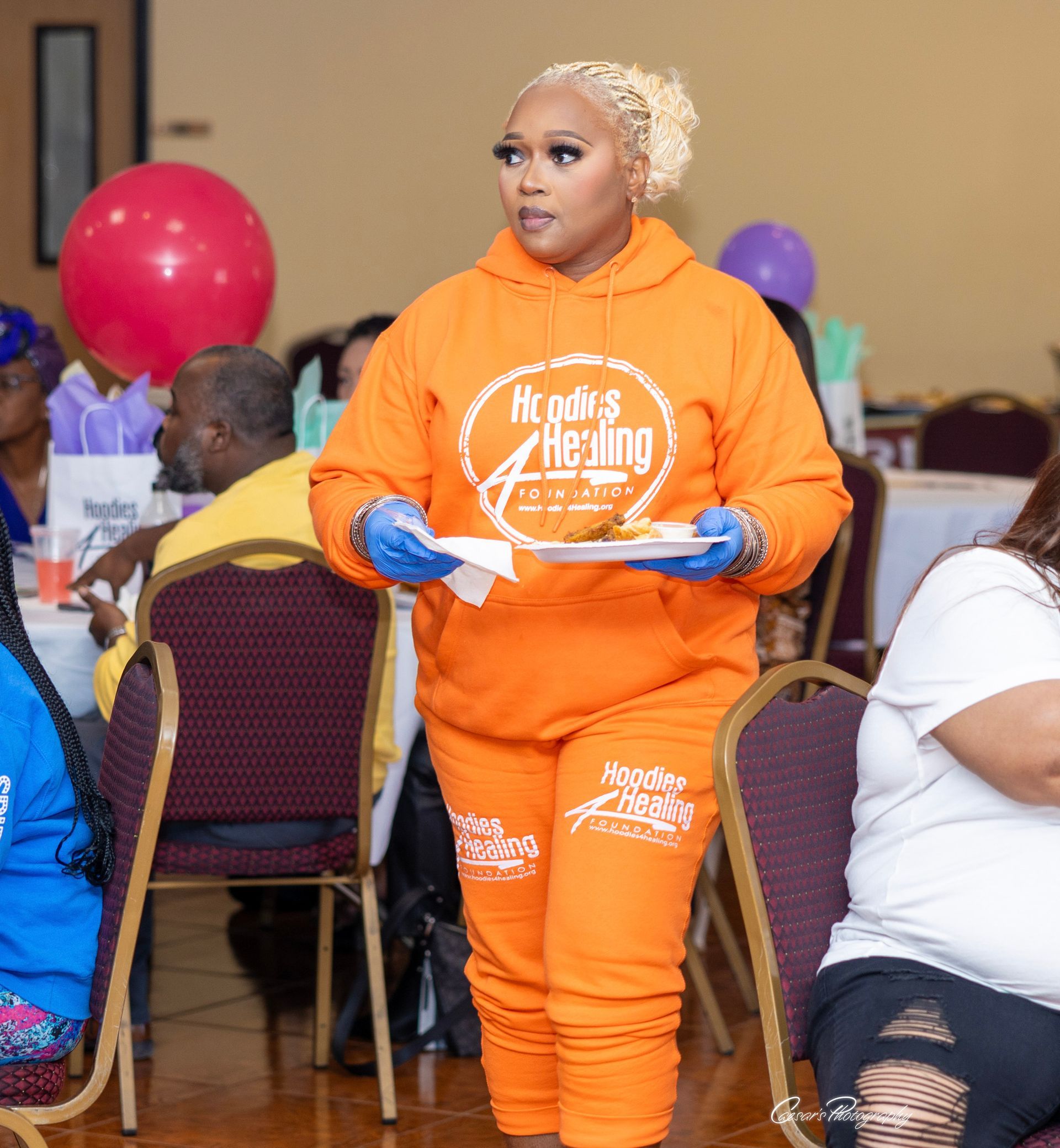 A woman in an orange hoodie is holding a plate of food