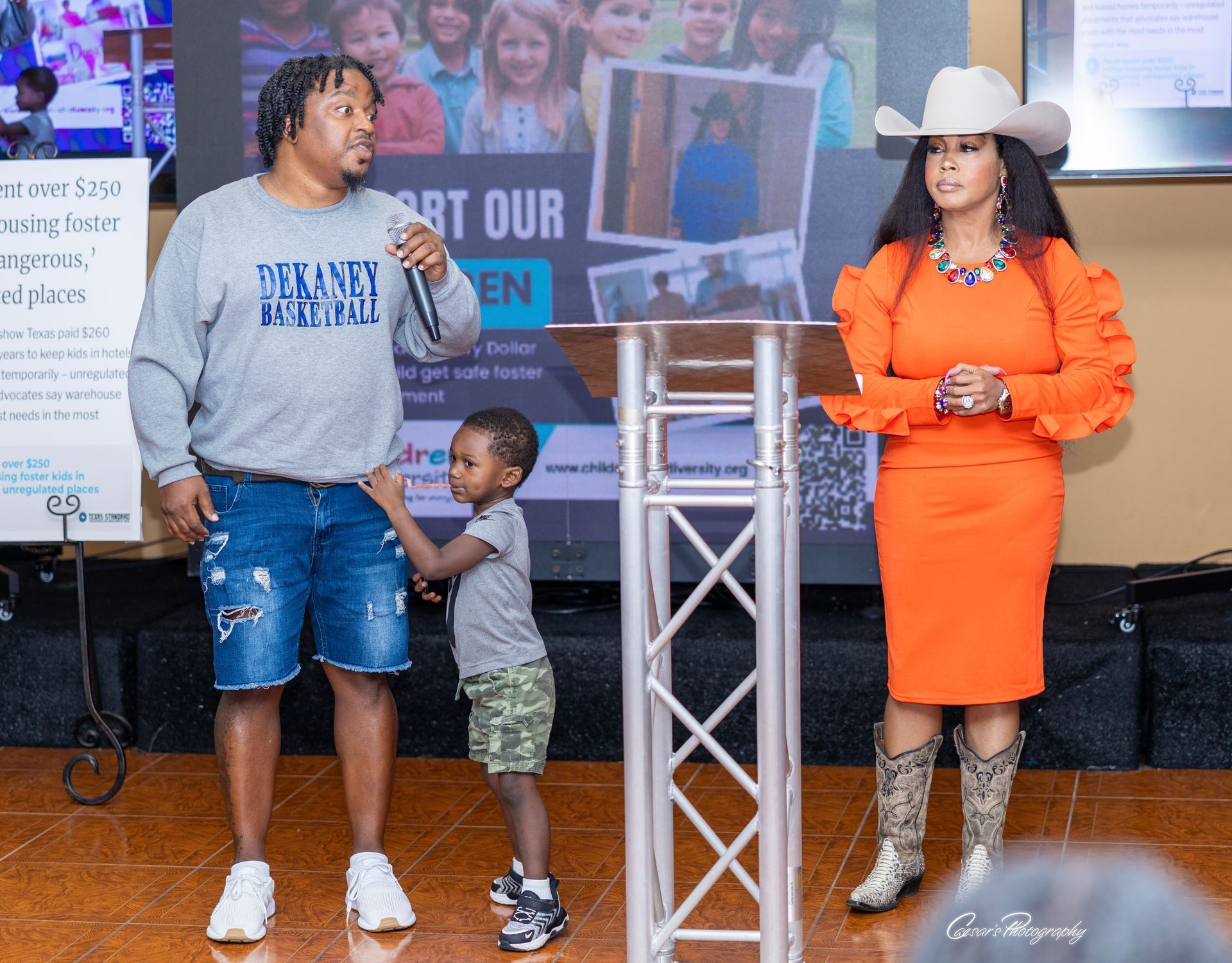 A man is holding a microphone while standing next to a woman and a child.