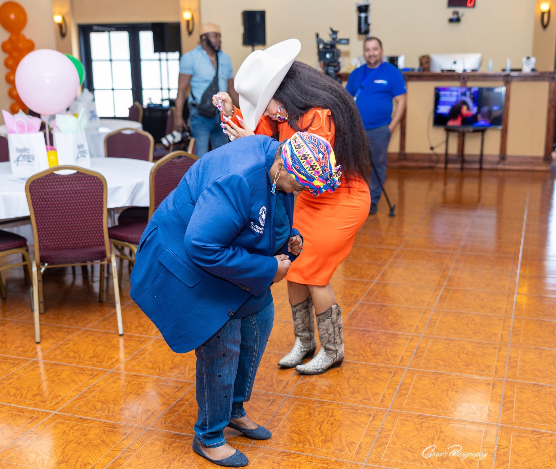 A woman in an orange dress is hugging a man in a blue suit