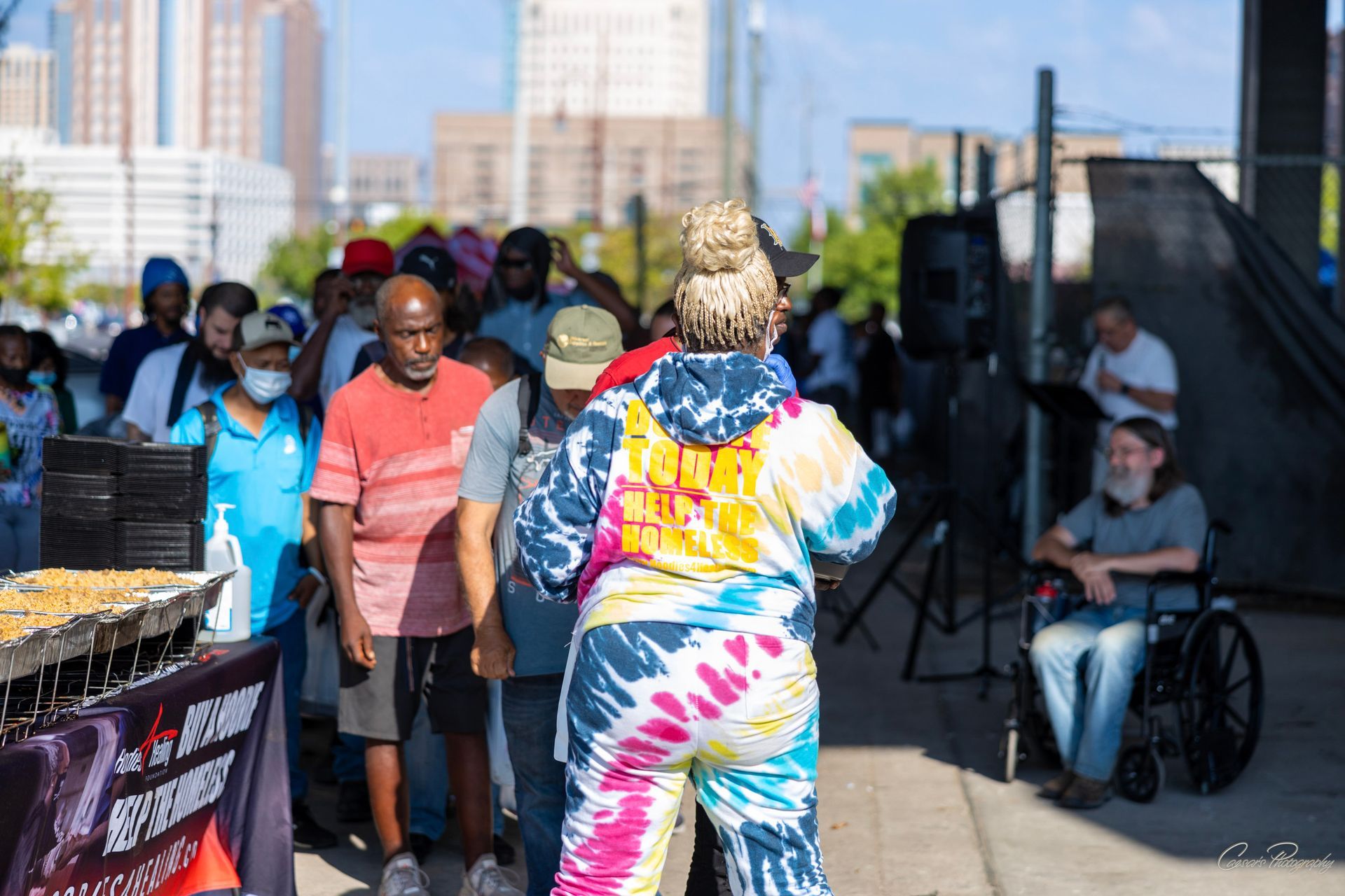 A woman in a tie dye shirt is dancing in front of a crowd of people.