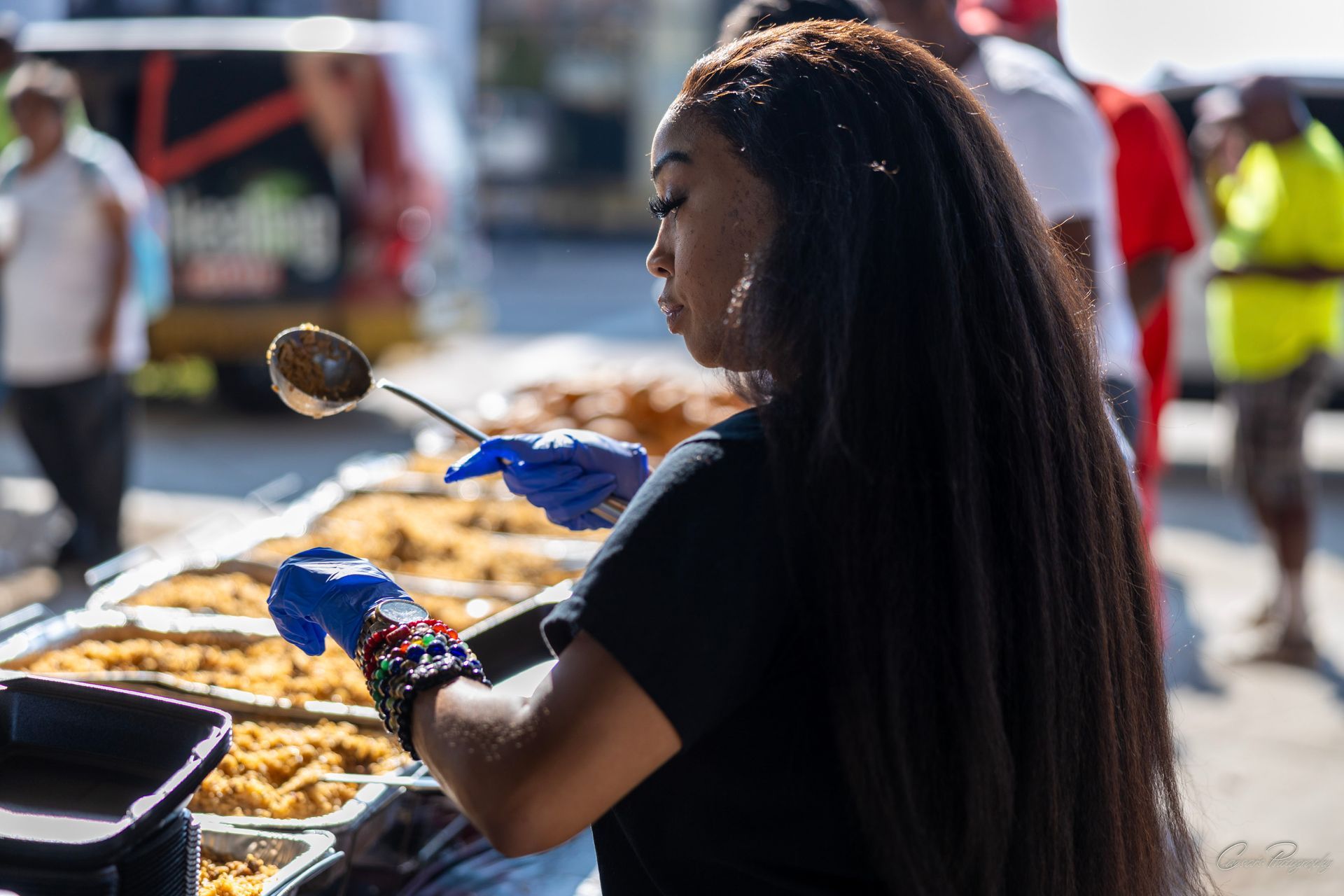 A woman is scooping food from a tray with a ladle.