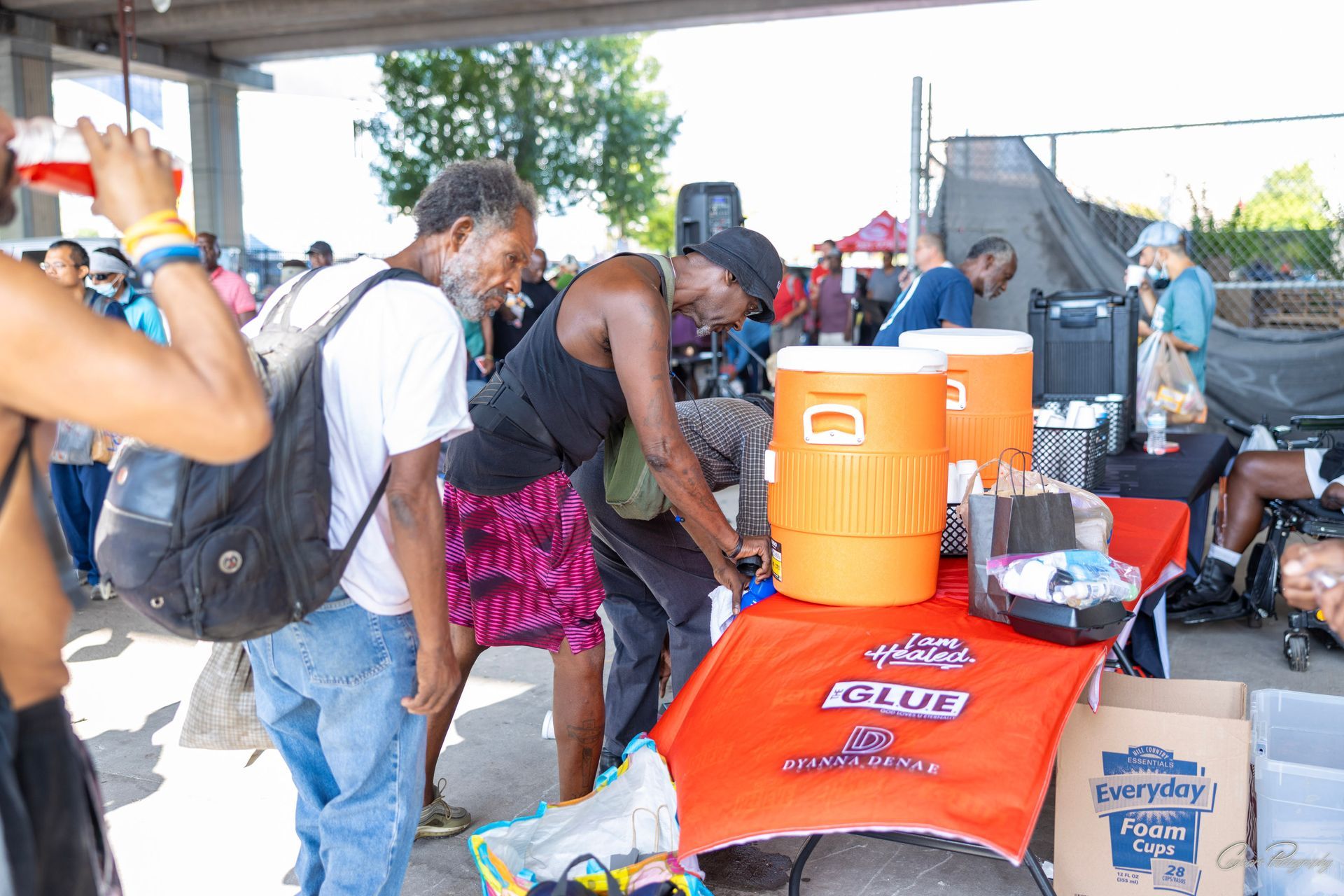 A group of people are standing around a table with coolers on it.