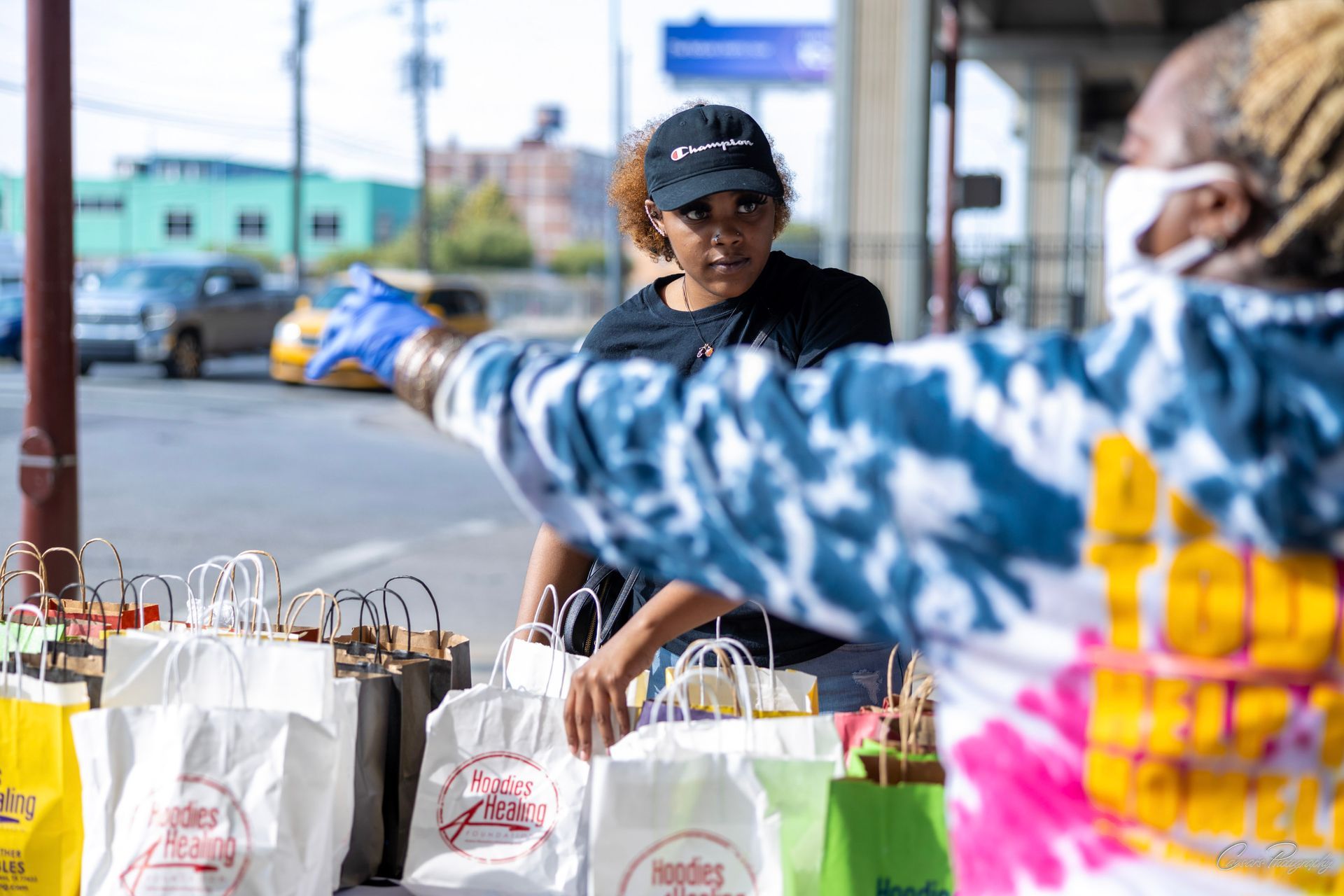 A woman wearing a mask is standing next to a man holding shopping bags.