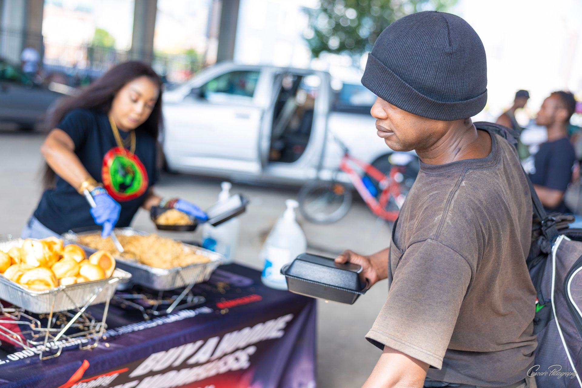 A man is getting food from a woman at a table.