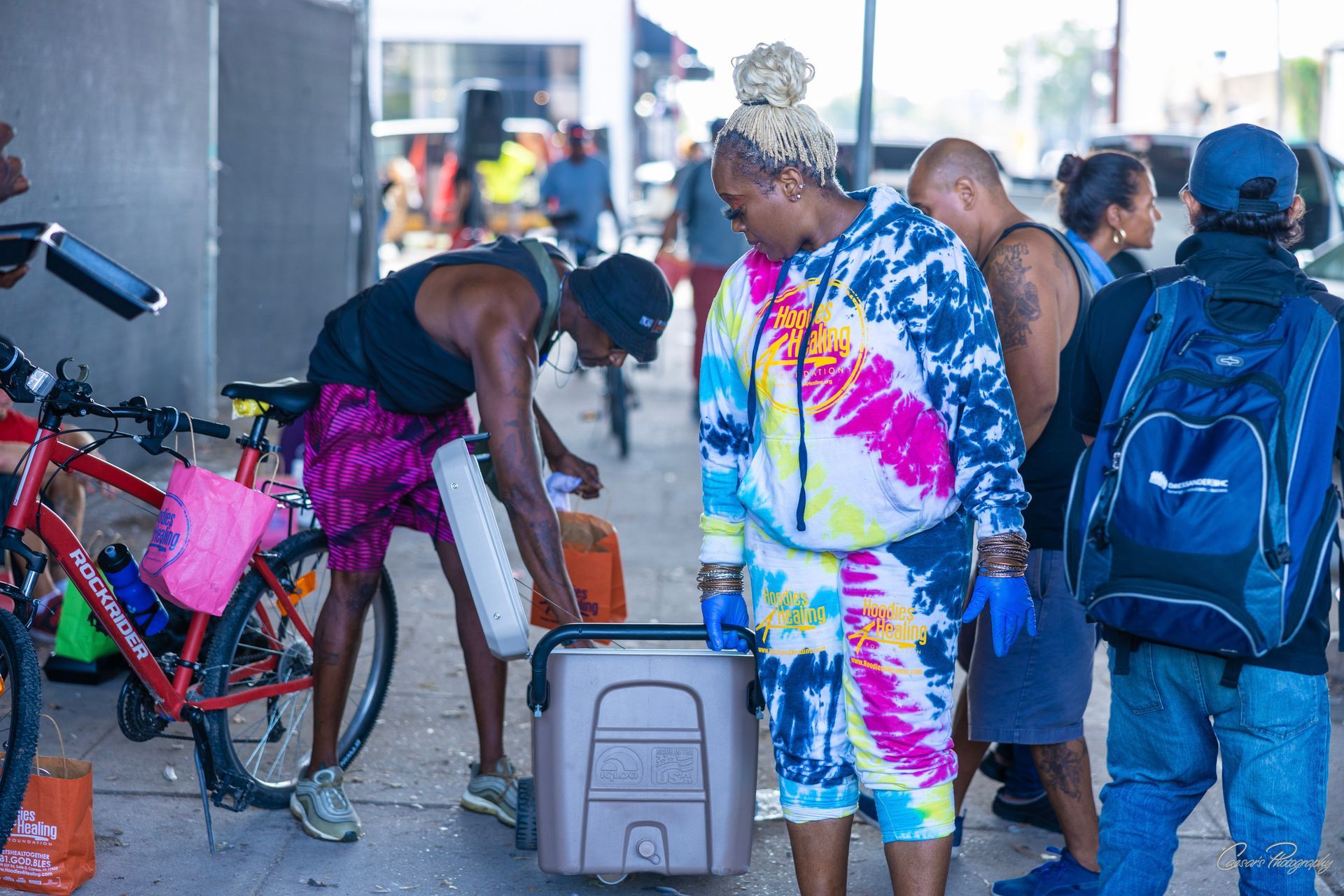 A group of people are standing on a sidewalk next to a bicycle.