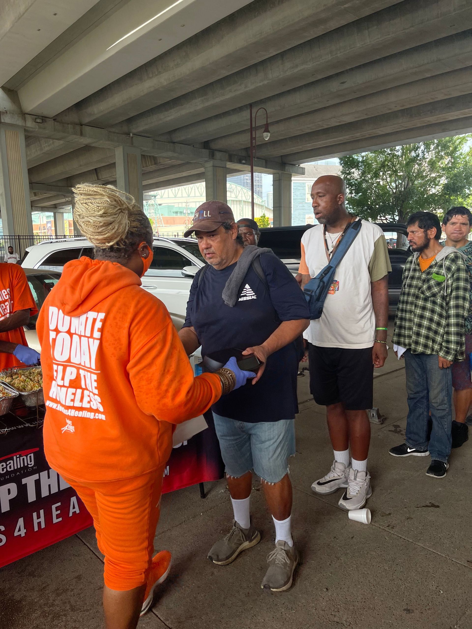 A woman in an orange hoodie is talking to a man