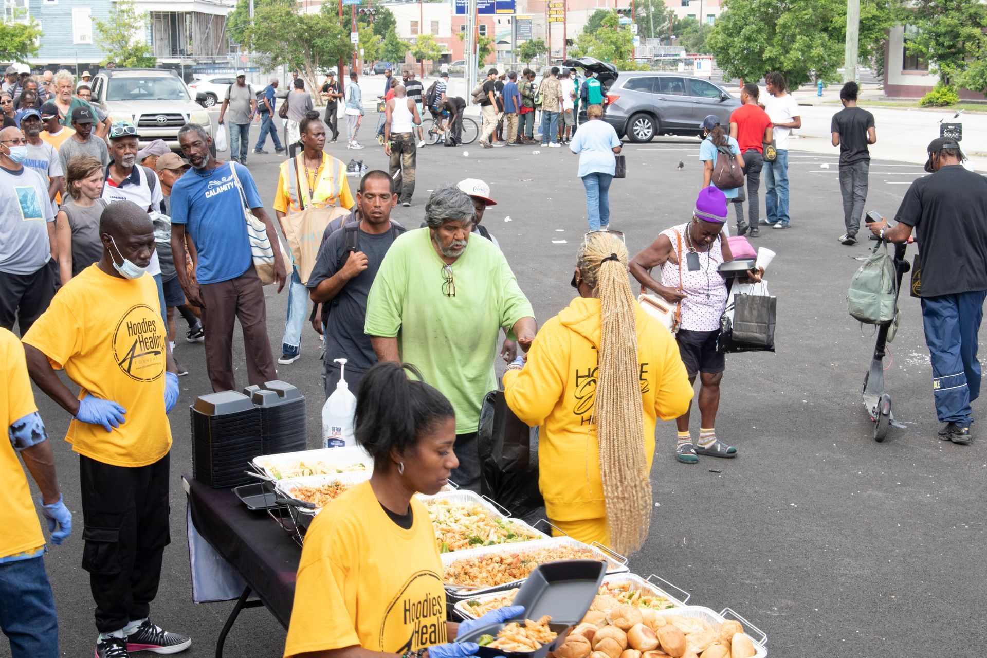 A group of people are standing around a table with food on it.