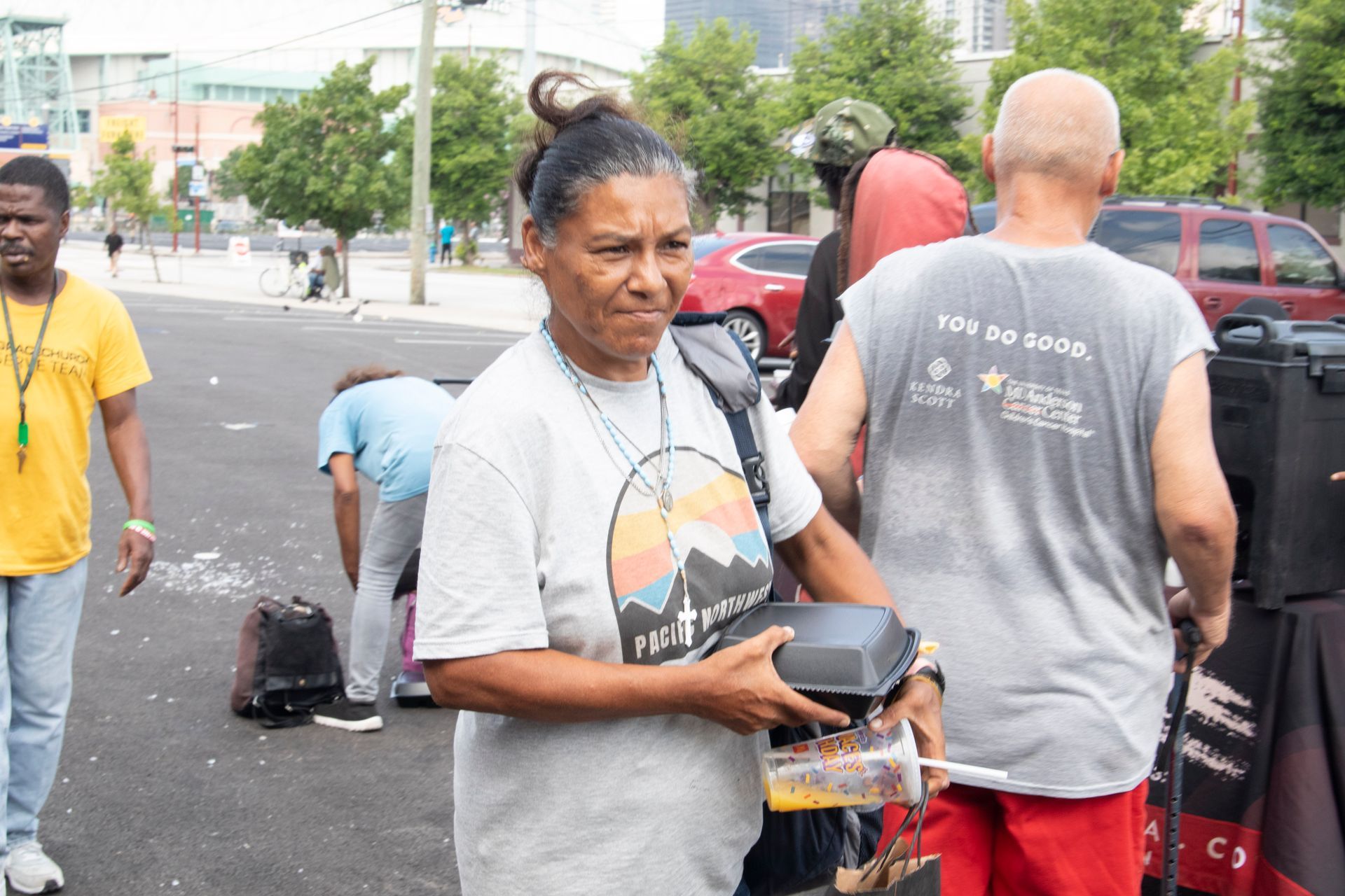A woman is carrying a container of food on a city street.