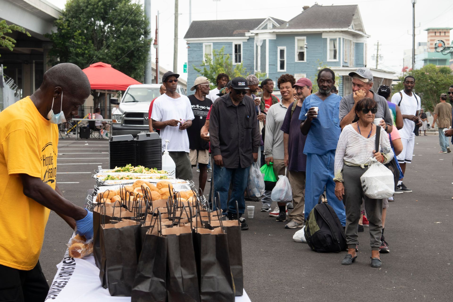 A man in a yellow shirt is serving food to a group of people