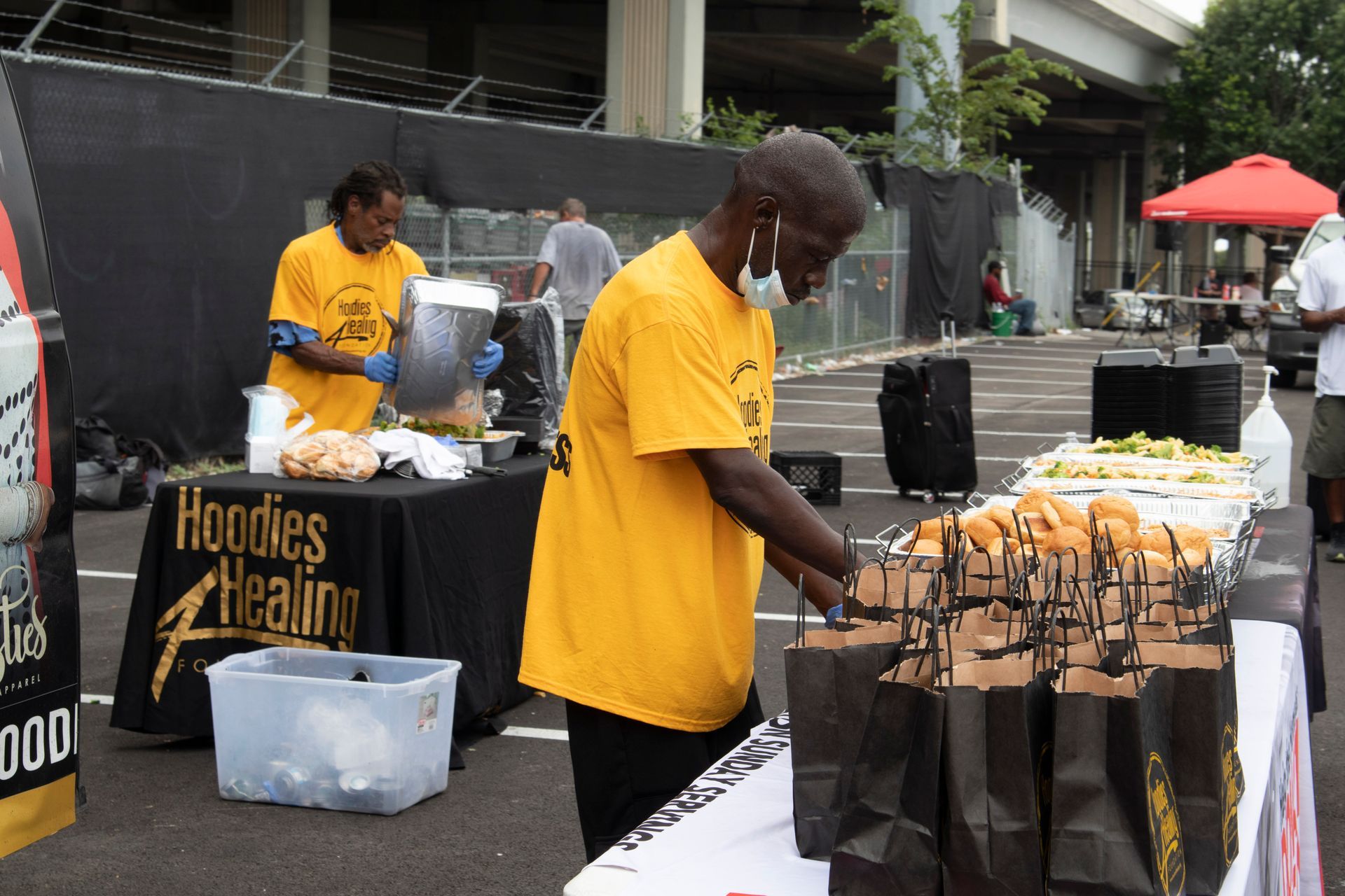 A man in a yellow shirt is standing in front of a table that says hoodies healing