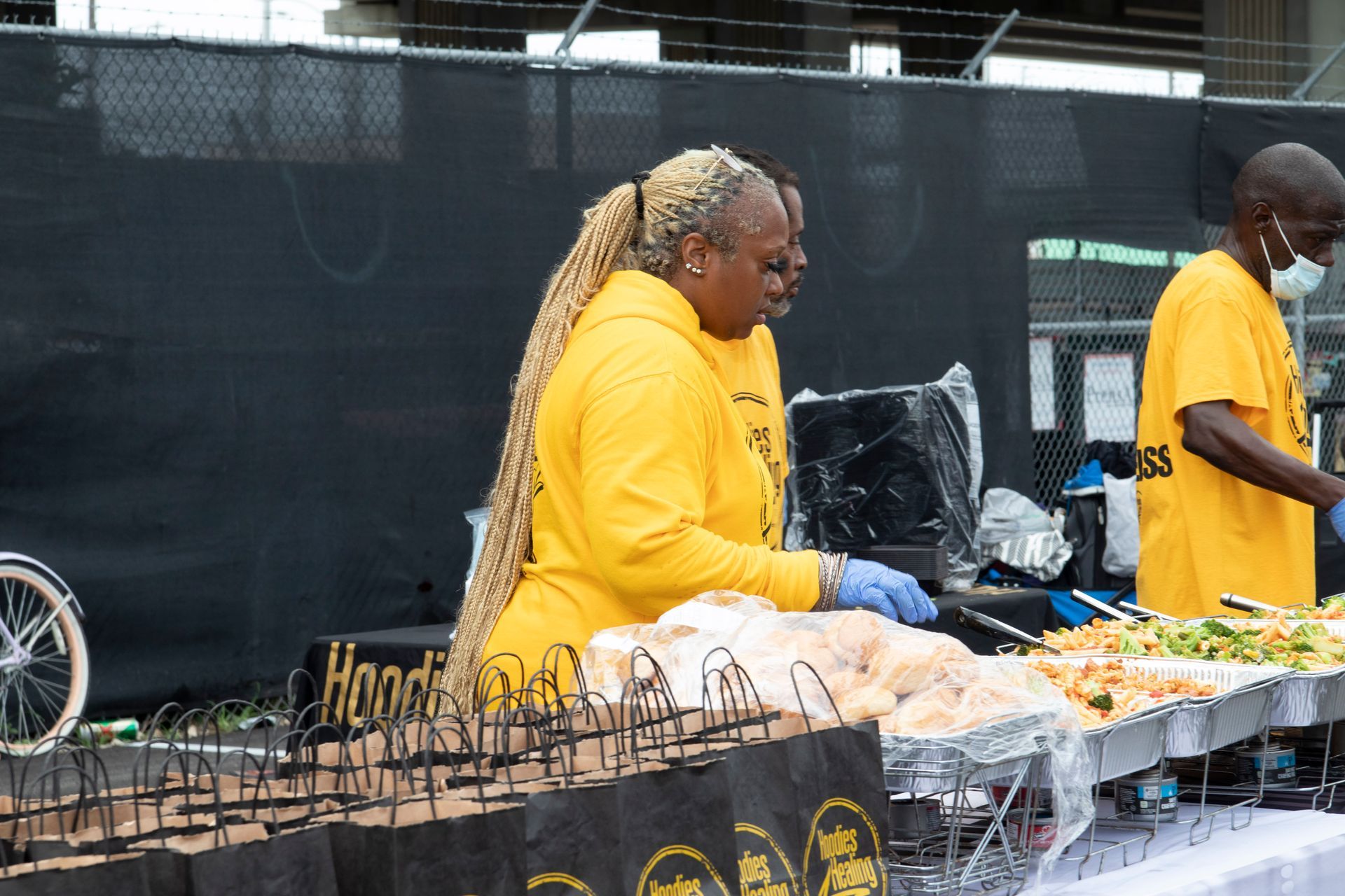 A woman in a yellow shirt is preparing food at a table.