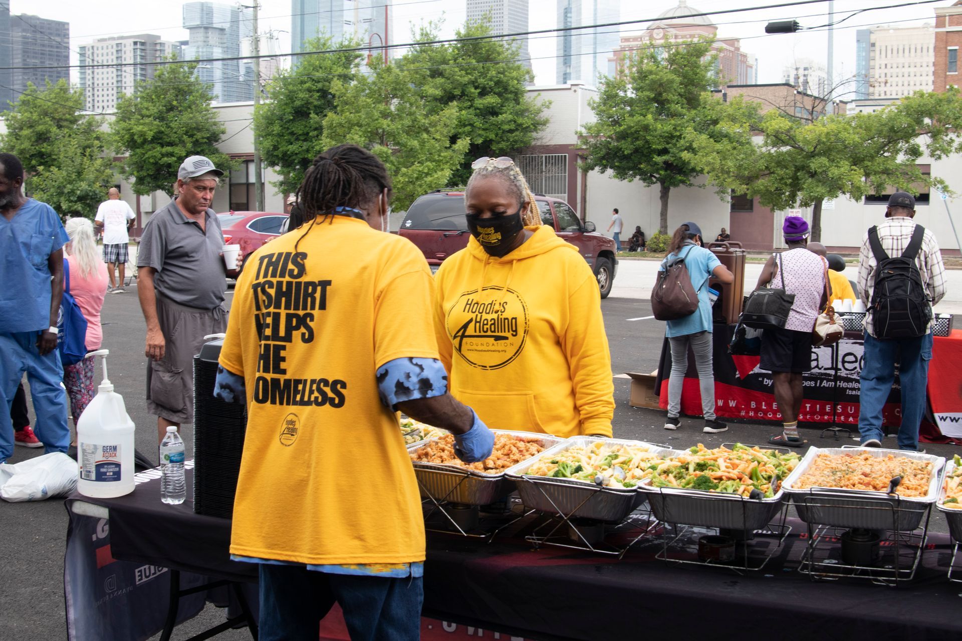 A group of people are standing around a table with plates of food.