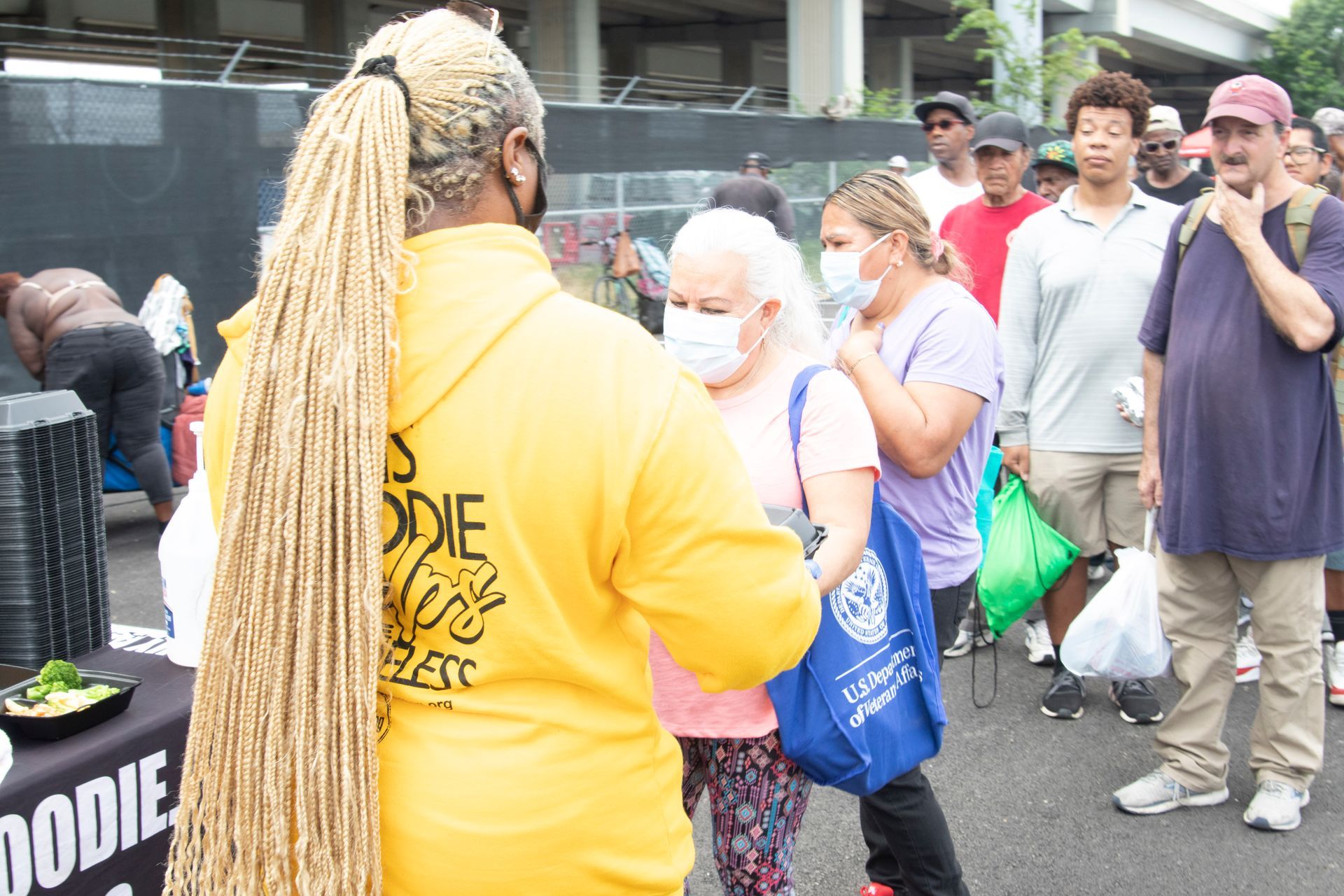 A woman in a yellow hoodie is standing in front of a crowd of people.