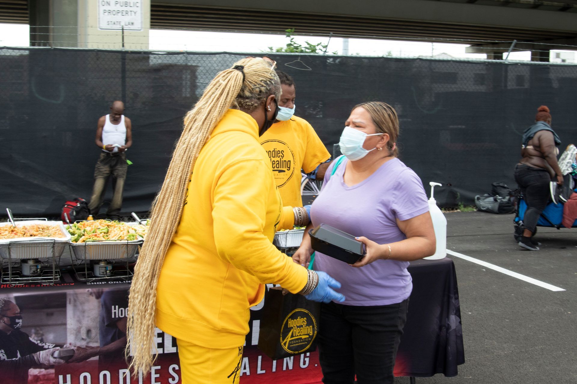 A woman wearing a mask is talking to a man in a yellow jacket.