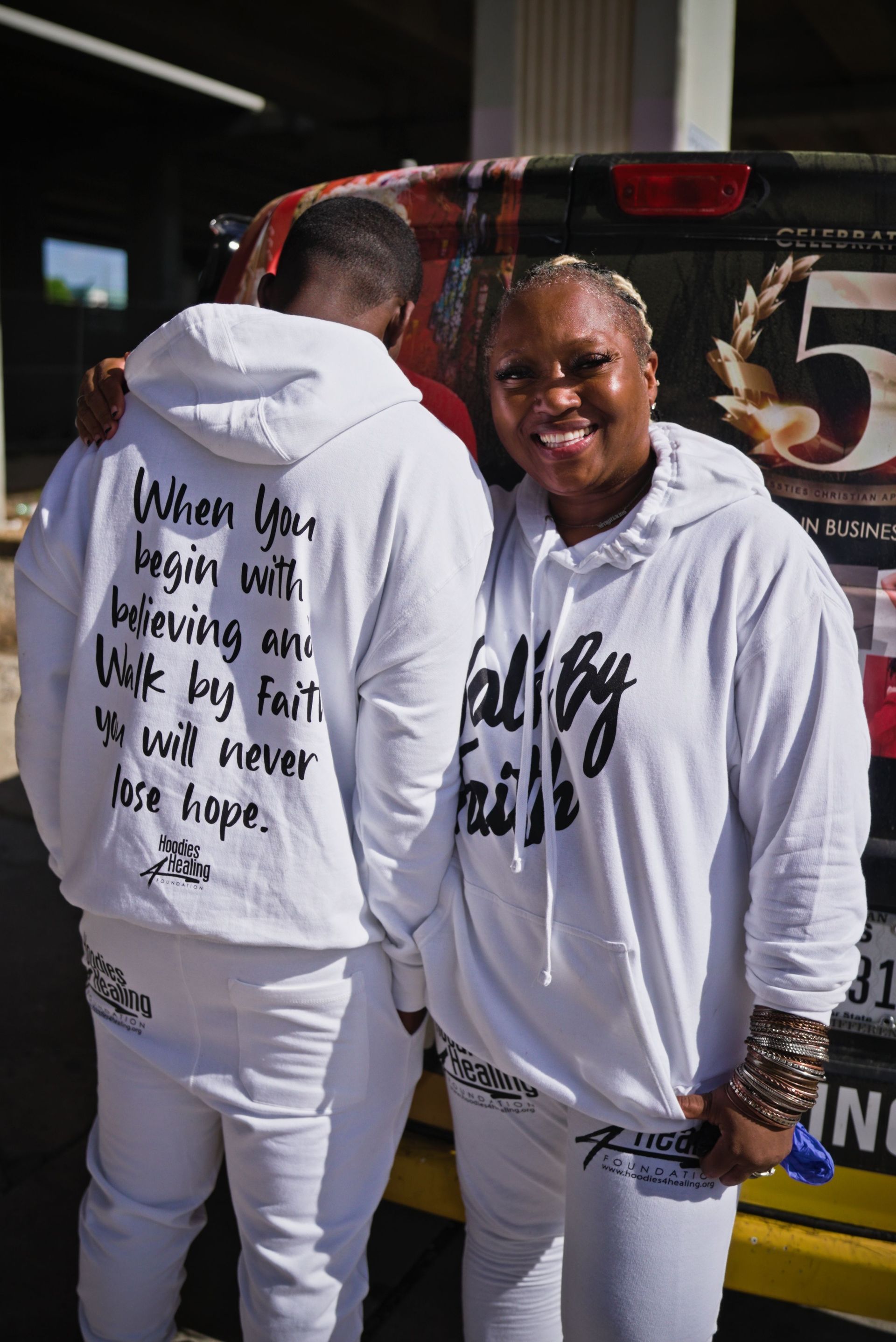 A man and a woman are standing next to each other wearing white hoodies.