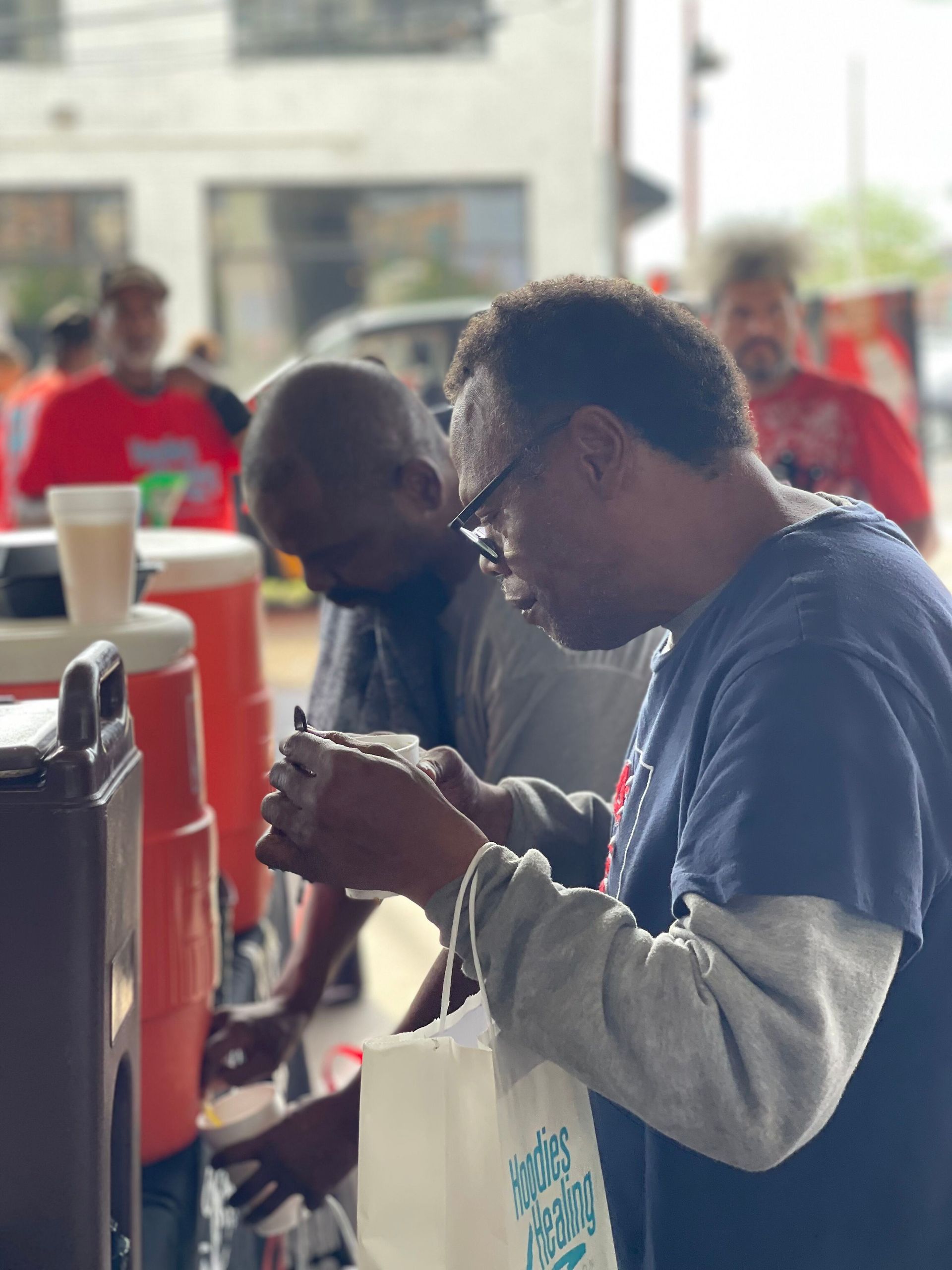 Two men are standing at a table looking at their phones