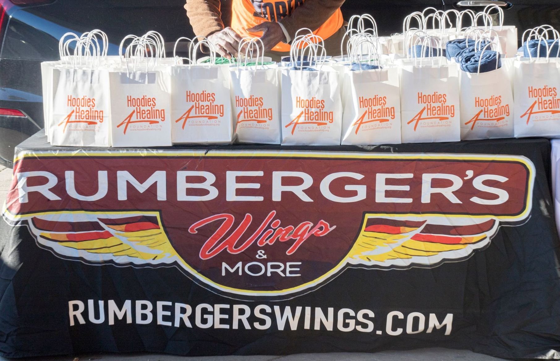 A group of people are gathered around a stack of pizza boxes.