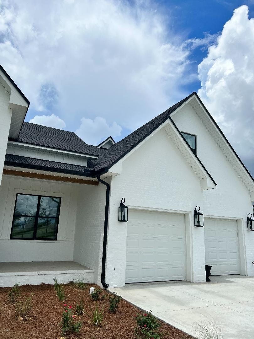 A white house with a black roof and gutter