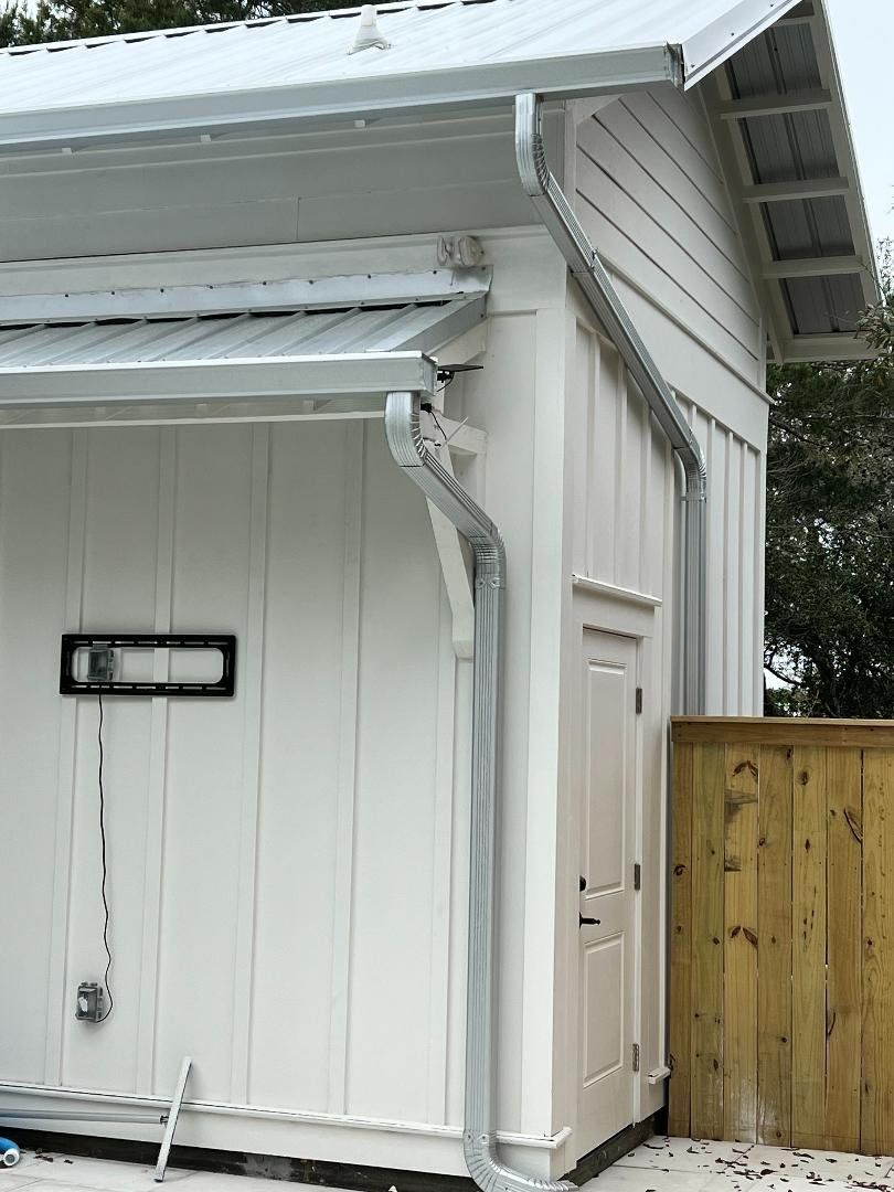 A white garage with a metal roof and a wooden fence.